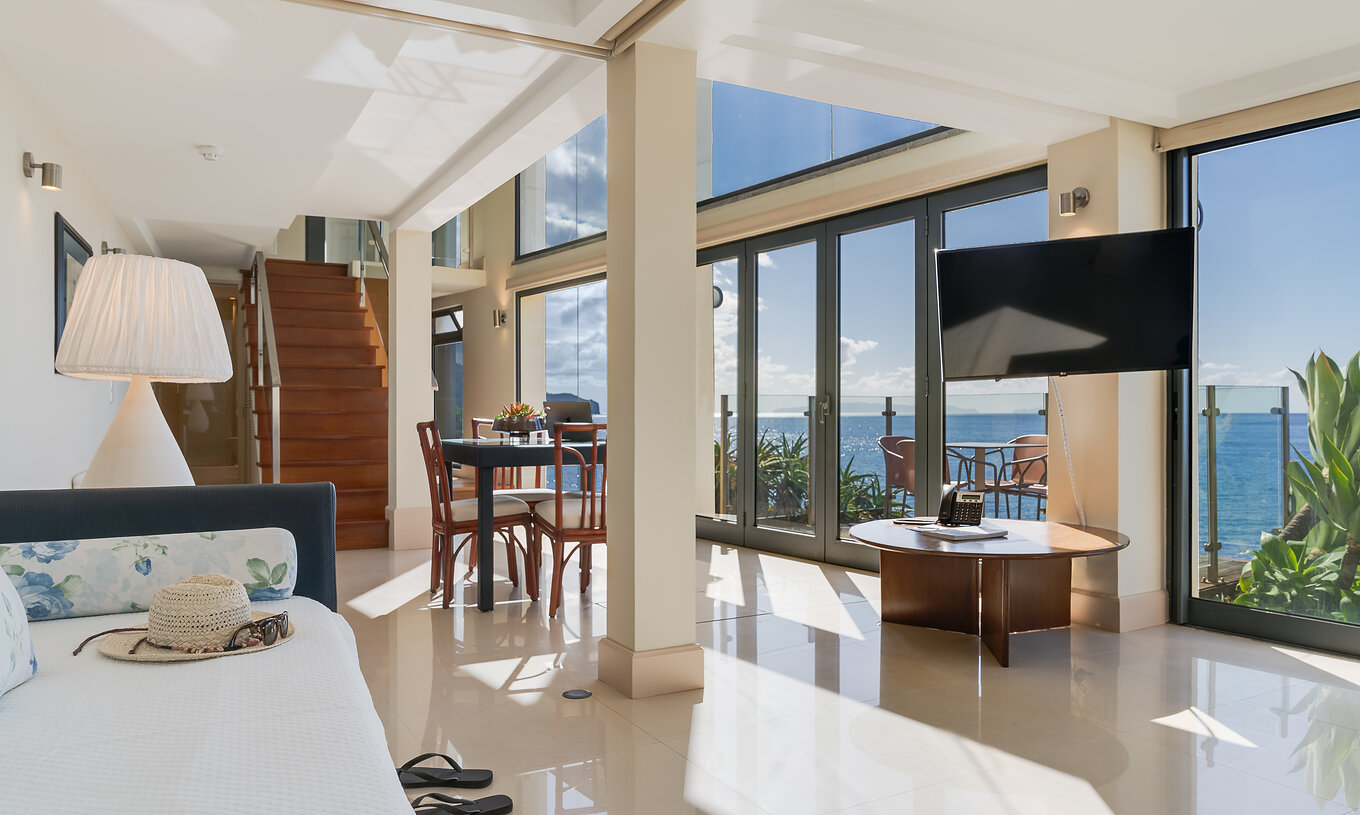 La Suite Duplex Vue Mer du Pestana Vila Lido Madeira a un grand salon avec vue sur la mer, avec canapé et table à manger