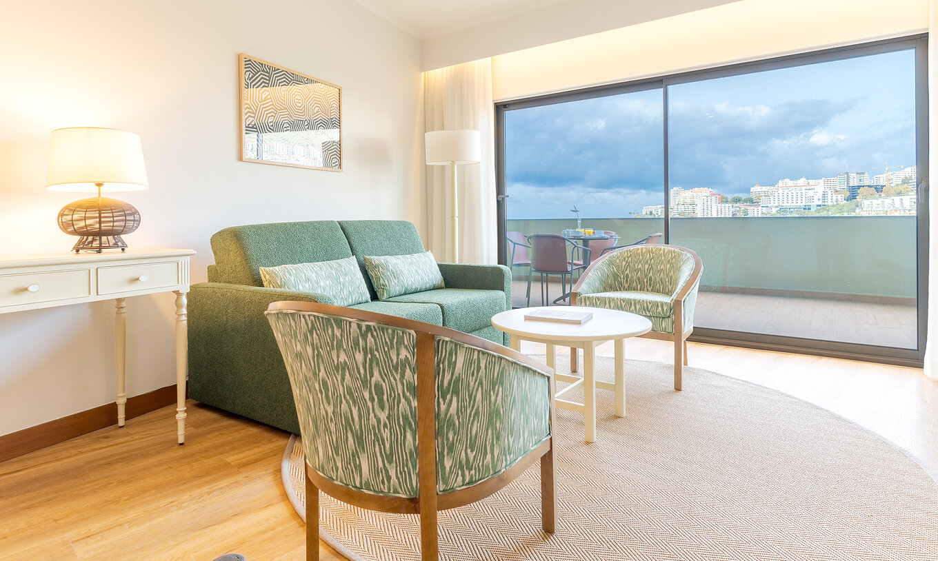 La Suite Supérieure Vue Mer Latérale du Pestana Vila Lido Madeira a un salon avec canapé, fauteuils et balcon