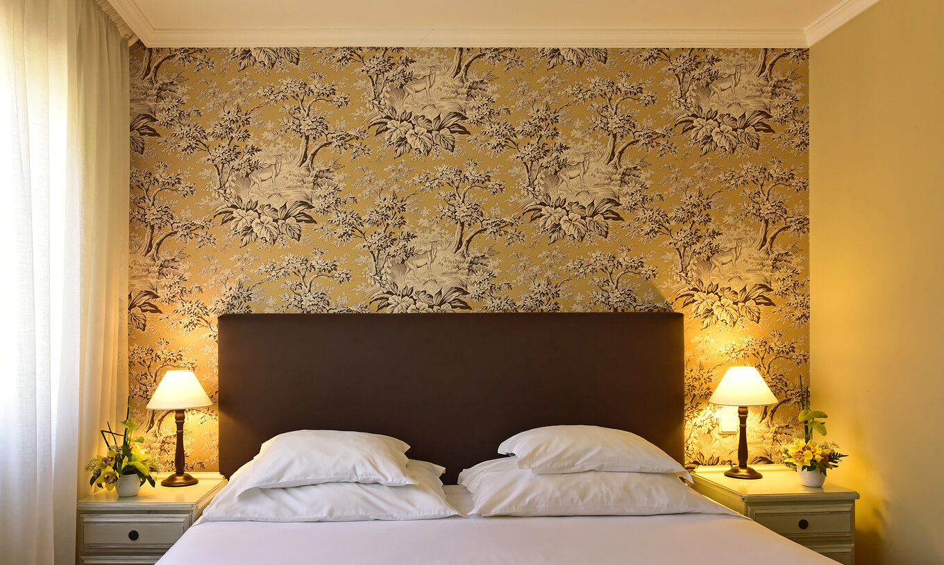 Le Twin Supérieur avec Jacuzzi du Pestana Village a un lit double avec tête de lit et couvre-lit marron, et papier peint