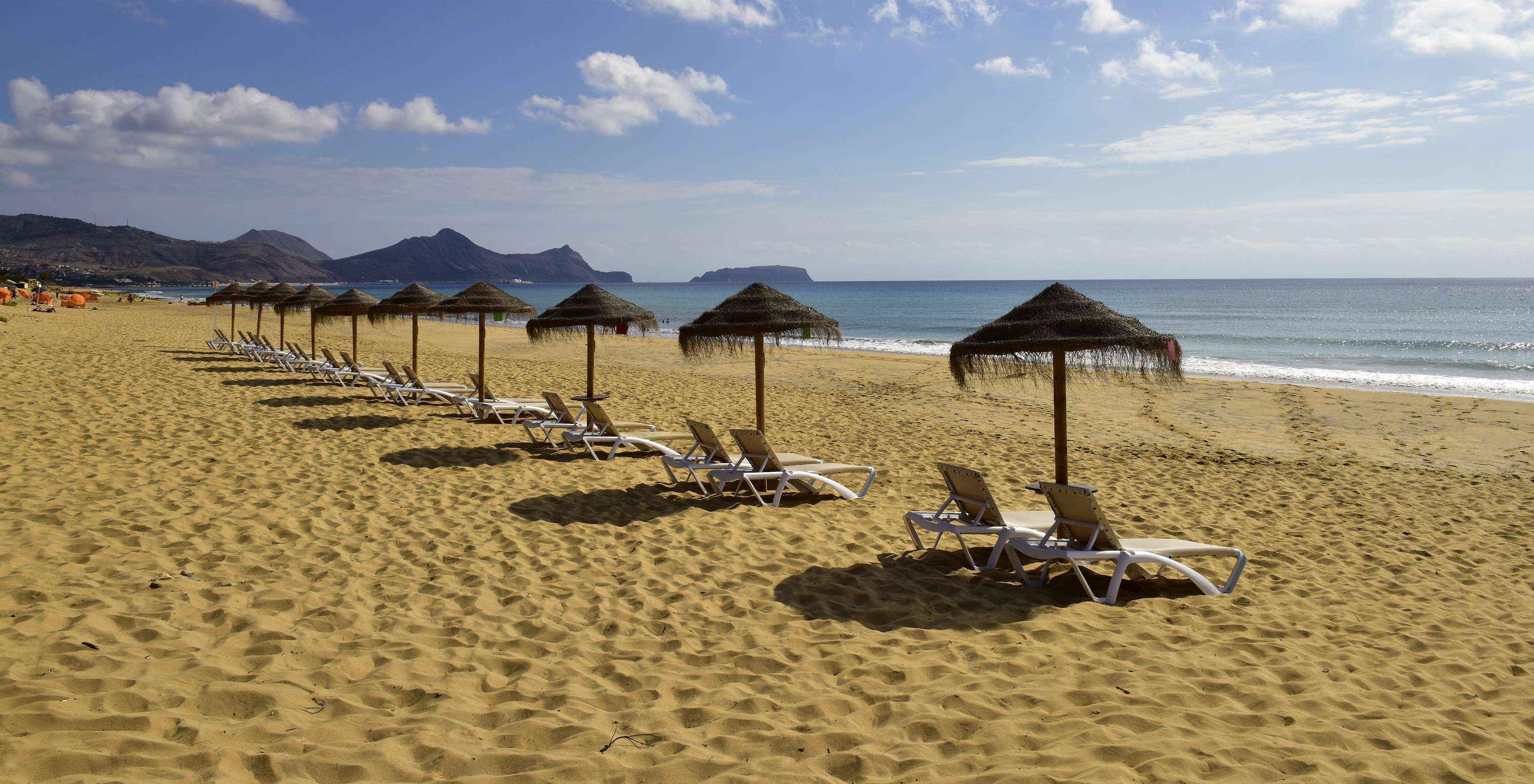 Plage de sable fin mer bleue et montagnes en arrière-plan du Pestana Porto Santo Hôtel Tout Inclus et Spa