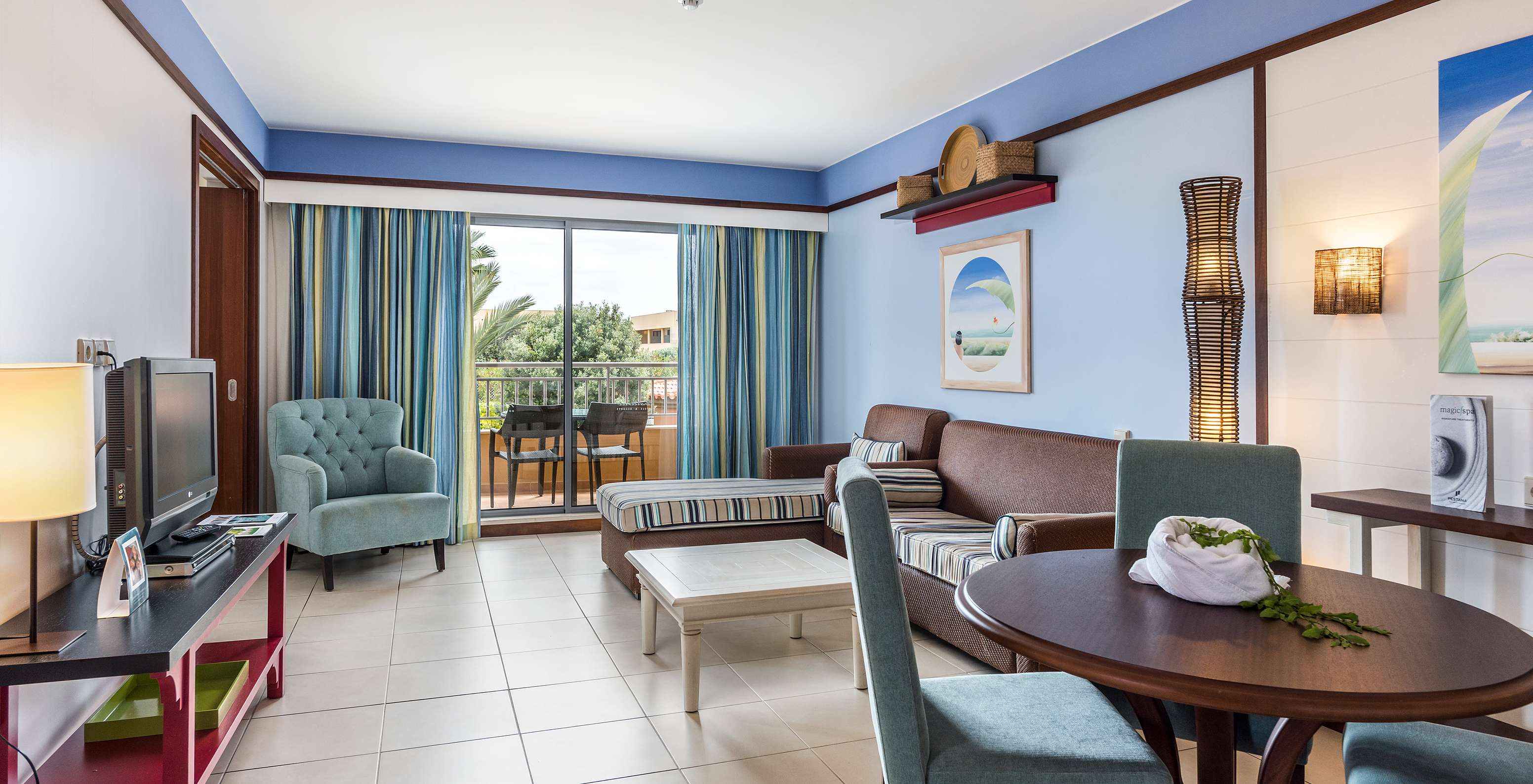 La Suite Appartement T2 du Pestana Porto Santo All Inclusive a un salon avec deux canapés, télévision et accès au balcon