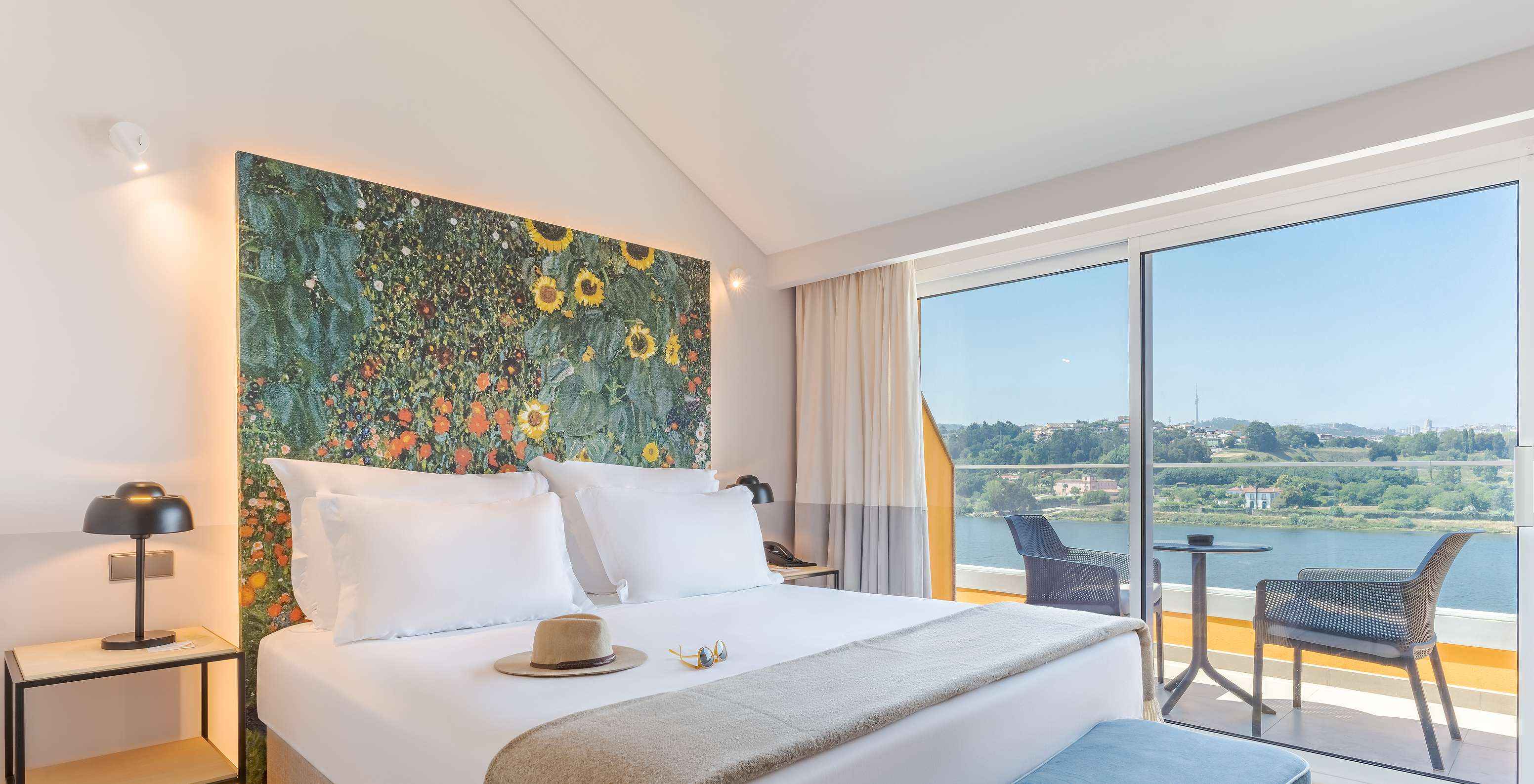 La Junior Suite du Pestana Douro Riverside a un lit double, une table de nuit avec lampe et un balcon avec vue
