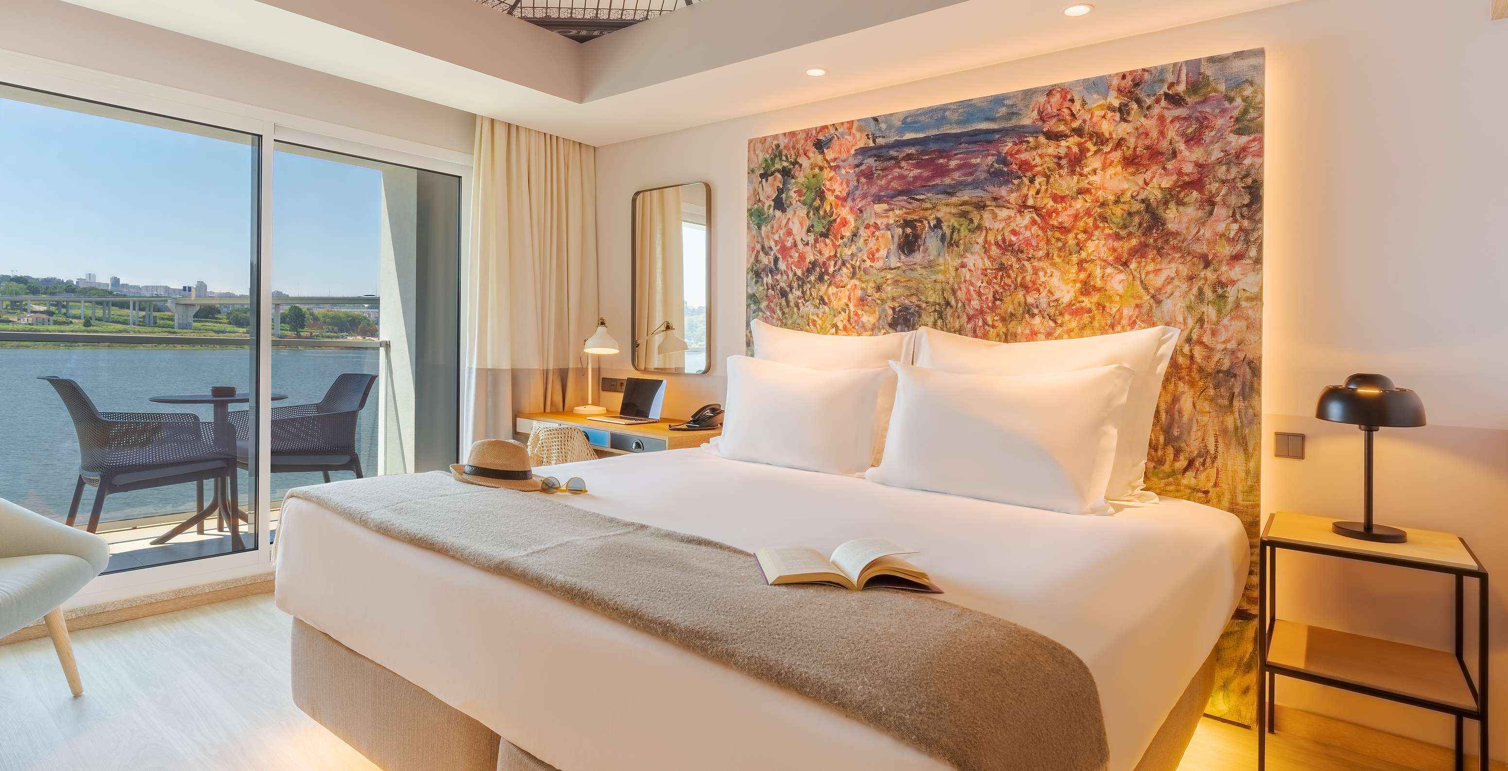 La chambre Deluxe River View du Pestana Douro Riverside a un lit double, table de nuit et balcon avec vue