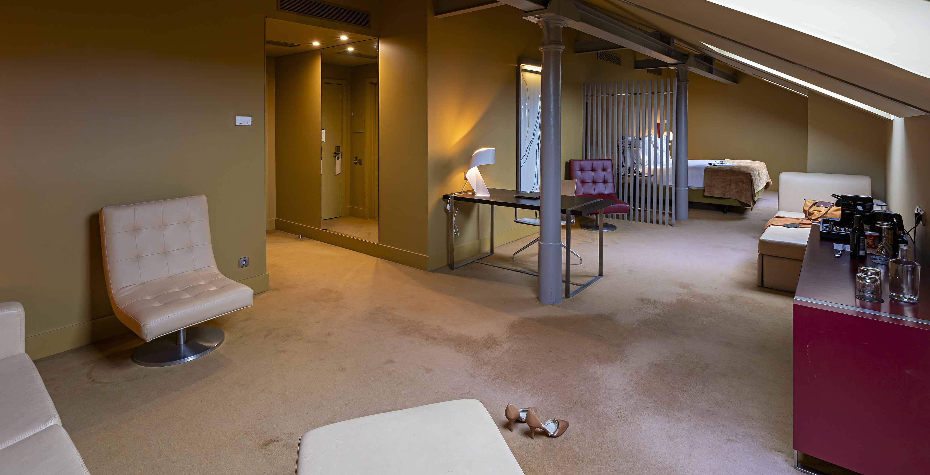 Le Loft Attique du Pestana Palácio do Freixo possède un canapé en cuir beige, un bureau et une armoire rouge