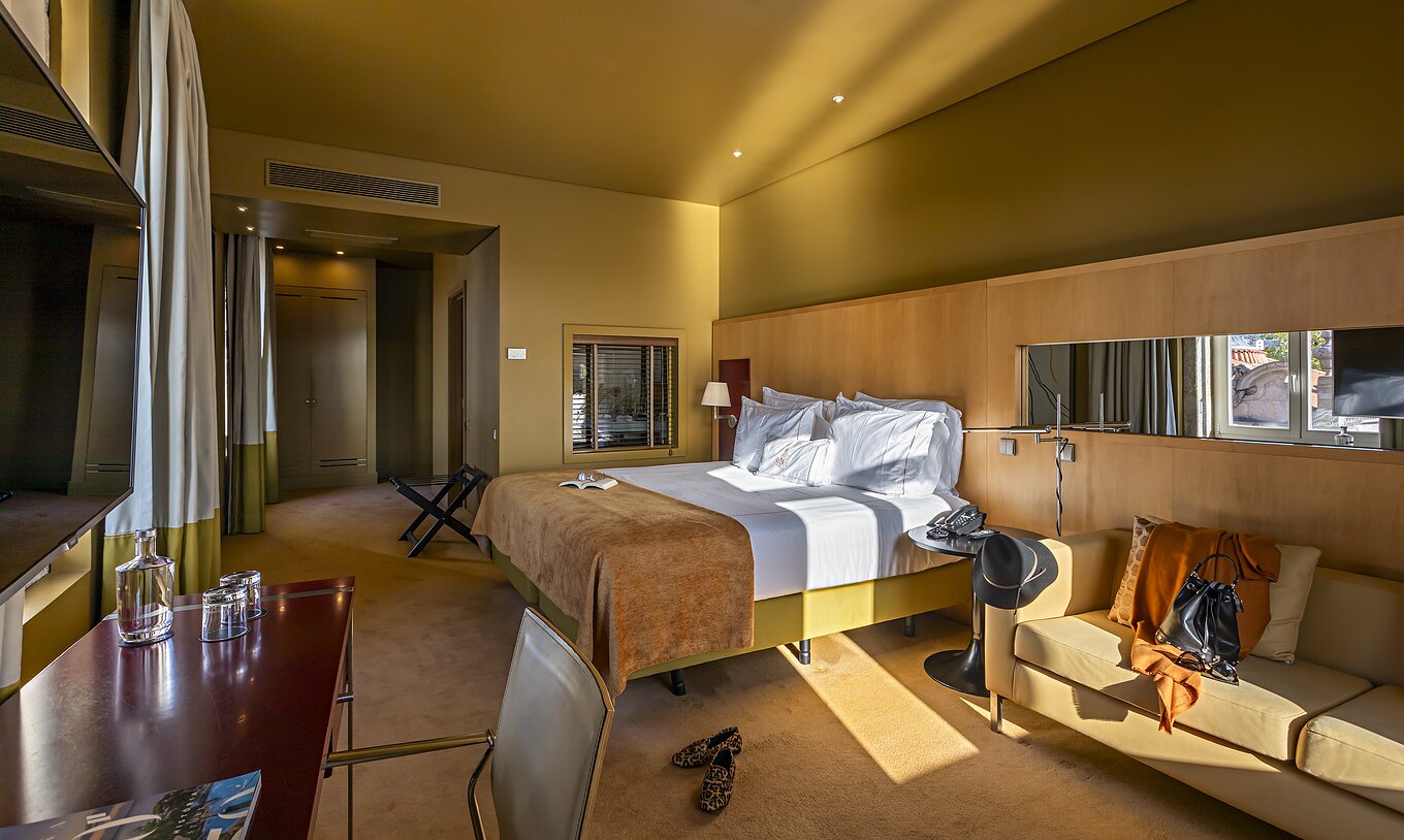 Le Deluxe Grand View comprend un lit double avec un plaid camel, un canapé et un bureau