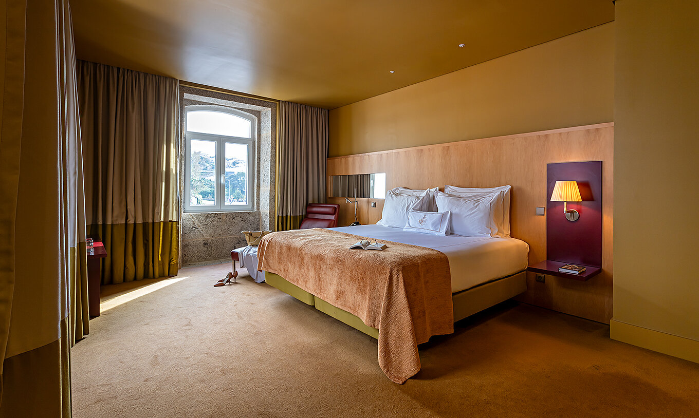 La Junior Suite comprend un lit double avec plaid beige et une fenêtre en pierre avec vue sur Le fleuve