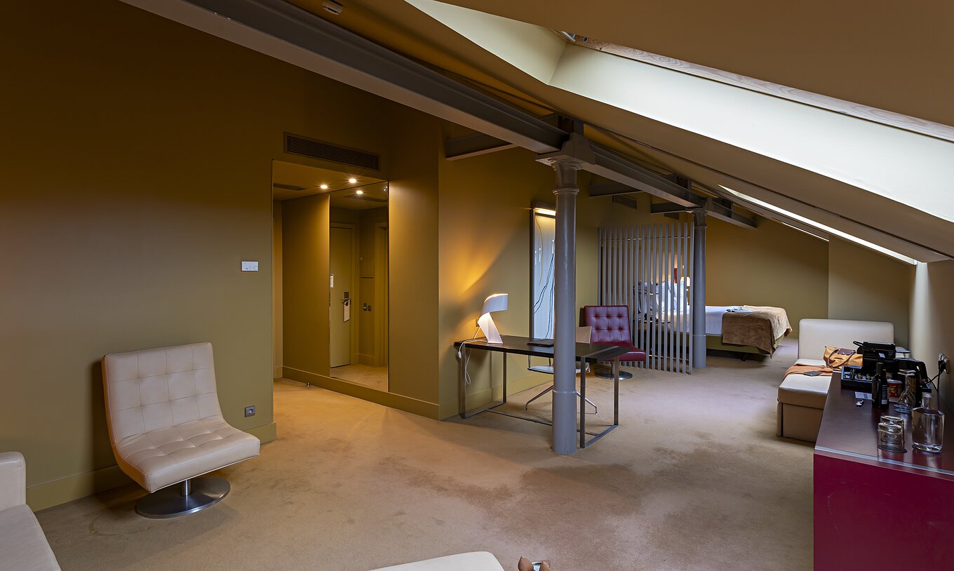 Le Loft Attique du Pestana Palácio do Freixo possède un canapé en cuir beige, un bureau et une armoire rouge