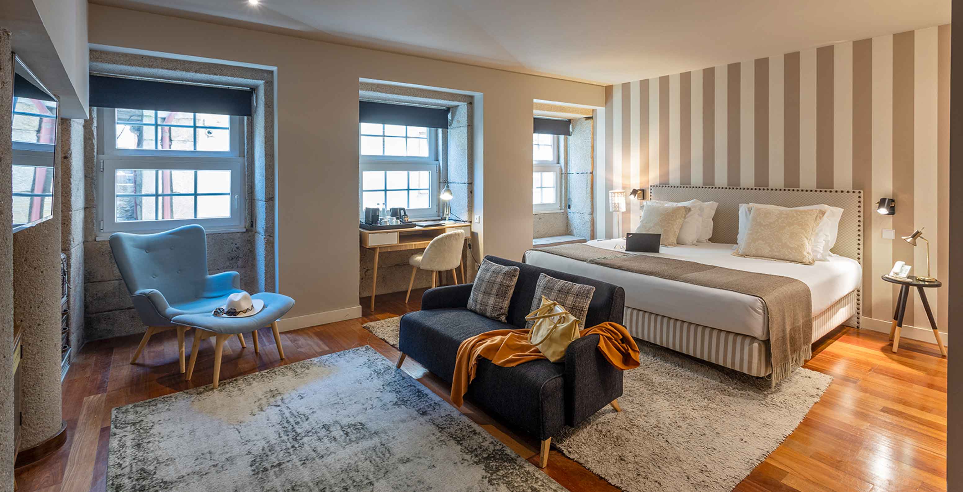 La Heritage Suite du Pestana Vintage Porto dispose d'un lit double, de deux canapés sur des tapis et de plusieurs fenêtres