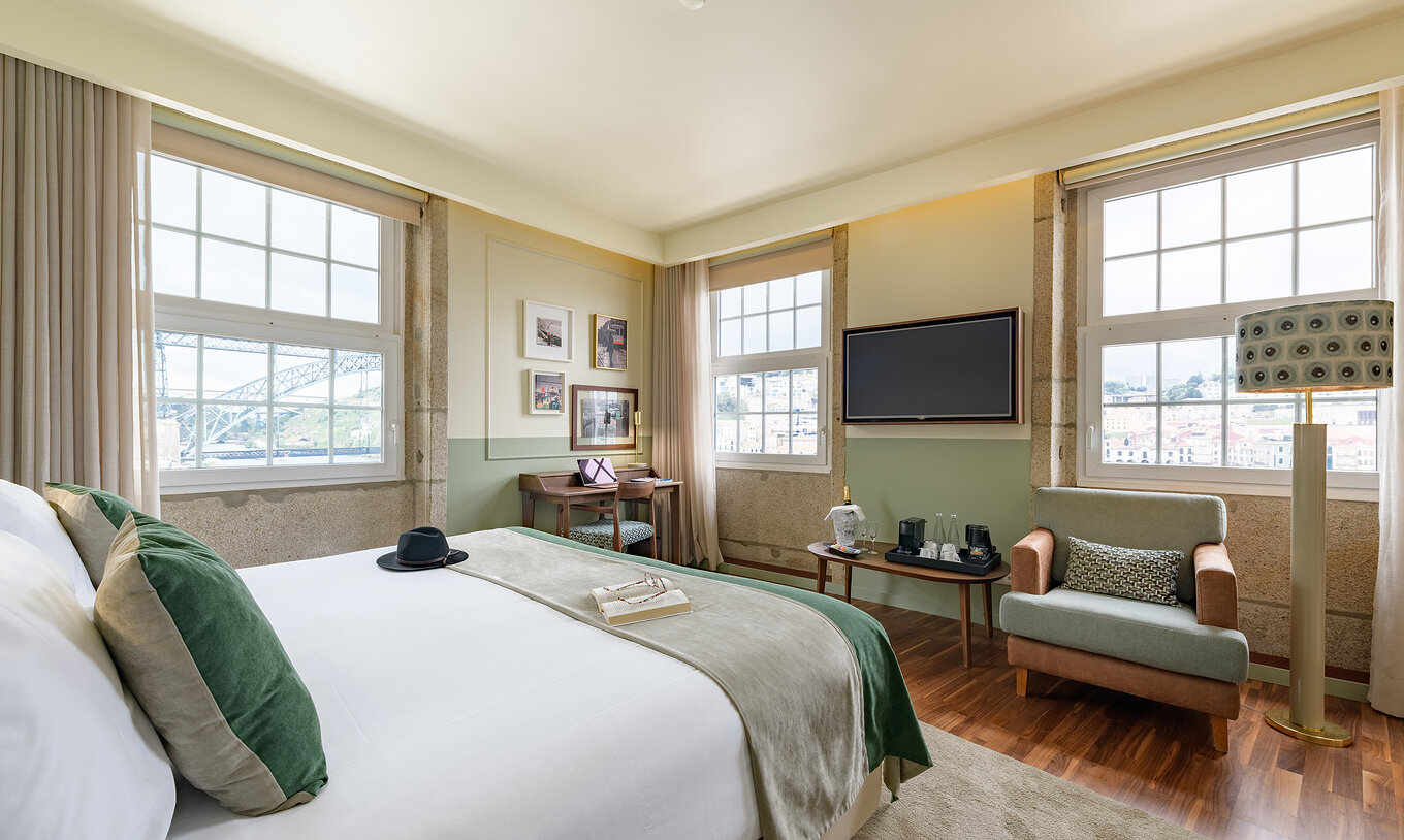 Le Vintage Grand View du Pestana Vintage Porto a trois grandes fenêtres avec vue sur le fleuve Douro et un lit double
