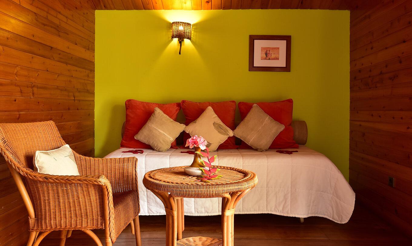 La Suite Standard du Pestana Equador Ilheu das Rolas a un mur vert, un lit, une table et une chaise en rotin