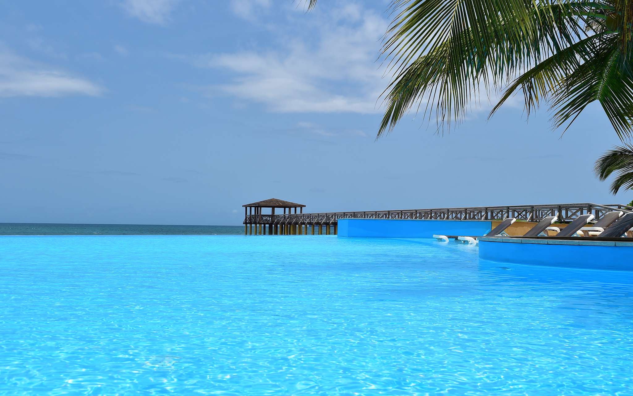 Vue paradisiaque de la piscine du Pestana São Tomé qui se fond avec la mer cristalline, un décor tropical idyllique