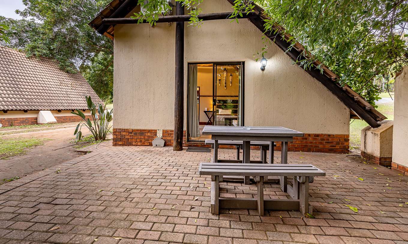 La Chambre Familiale du Pestana Kruger Lodge a une zone extérieure avec une table en bois avec vue sur le jardin