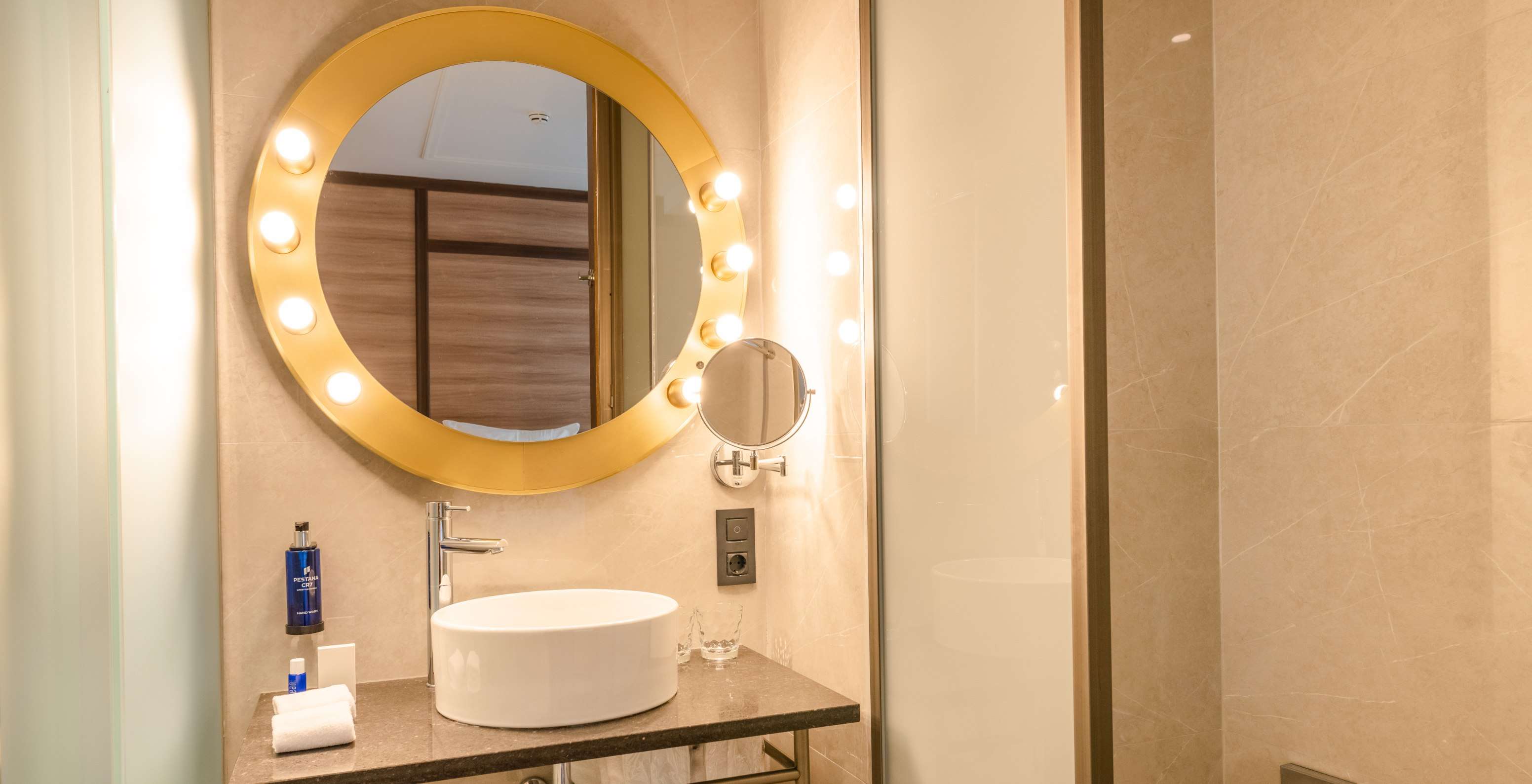 La Chambre Cozy du Pestana CR7 Gran Vía Madrid dispose d'une salle de bain avec un miroir rond avec des lumières