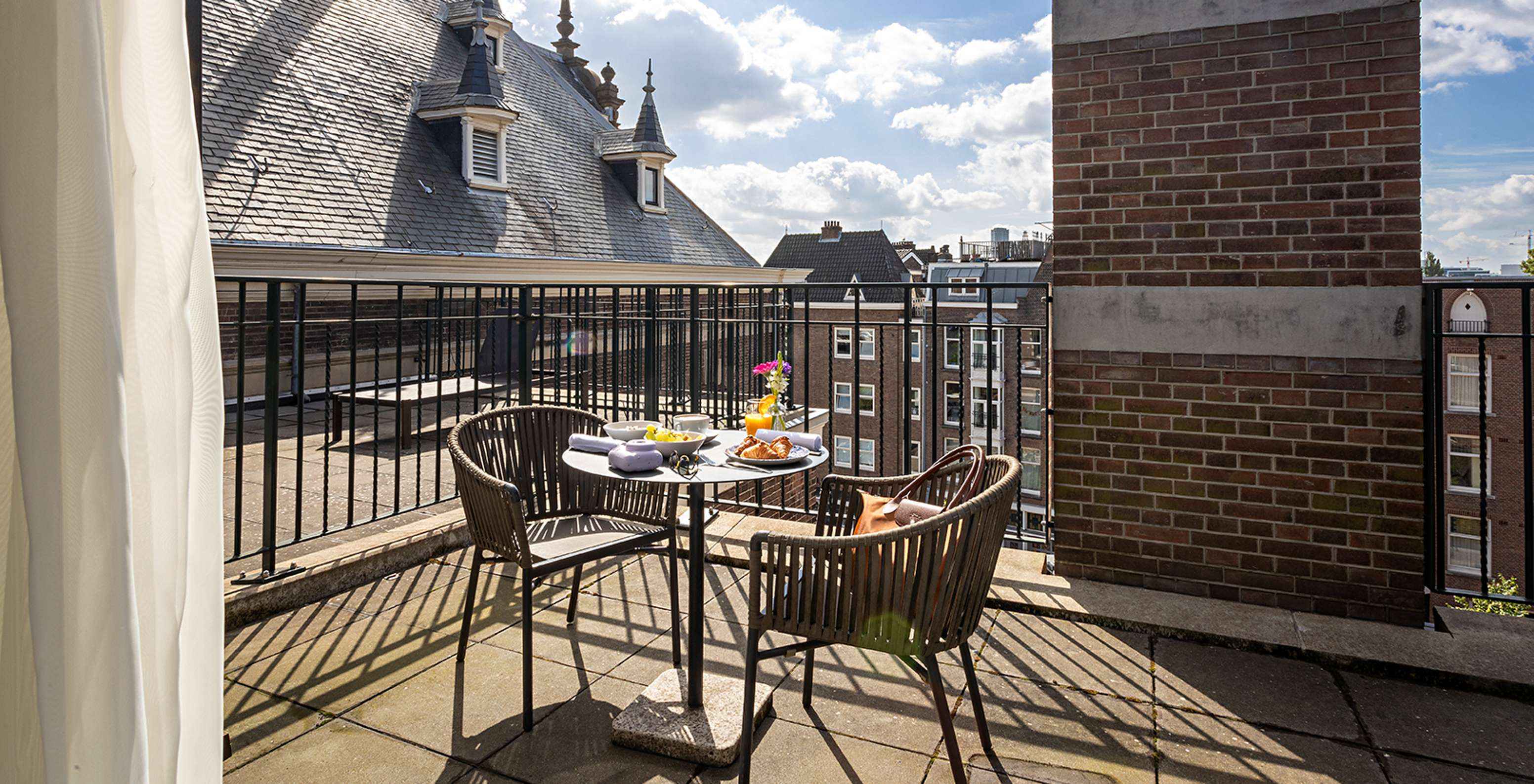La chambre Supérieure avec Terrasse du Pestana Amsterdam Riverside a un balcon, avec une table avec nourriture et deux chaises