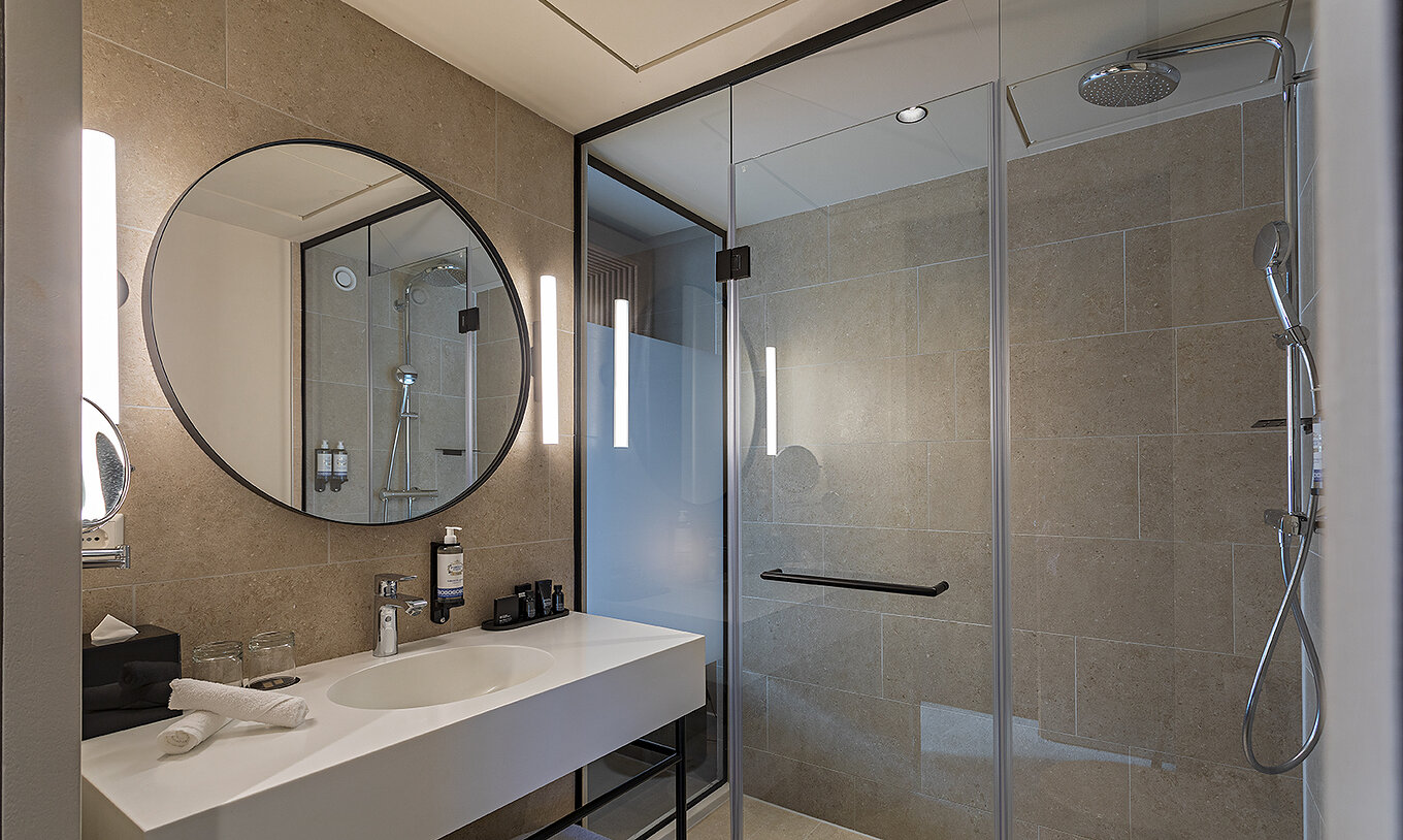 La chambre Executive du Pestana Amsterdam Riverside a une salle de bain avec miroir, lavabo, serviettes et douche