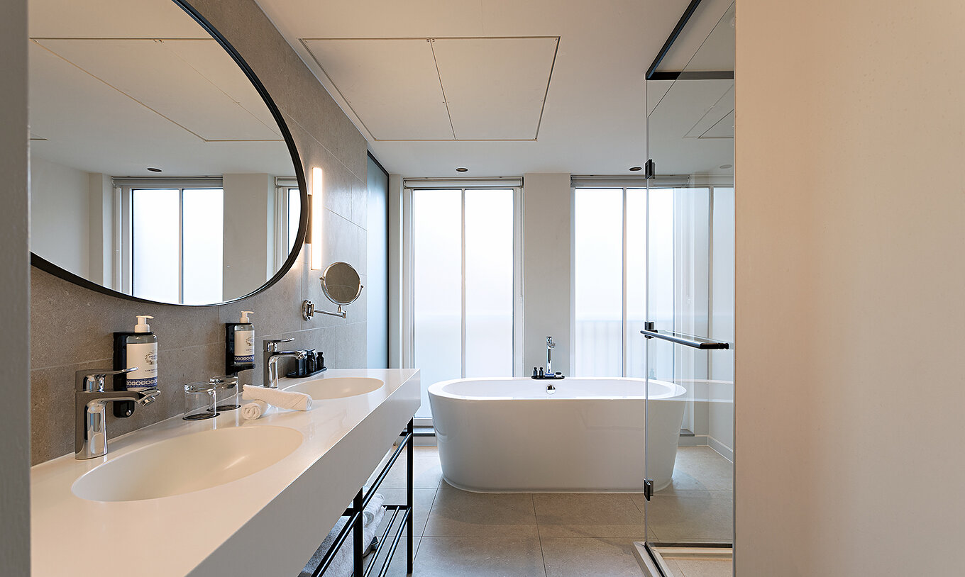 La chambre Premium - Vue Rivière du Pestana Amsterdam Riverside a une salle de bain avec miroir, deux lavabos et baignoire