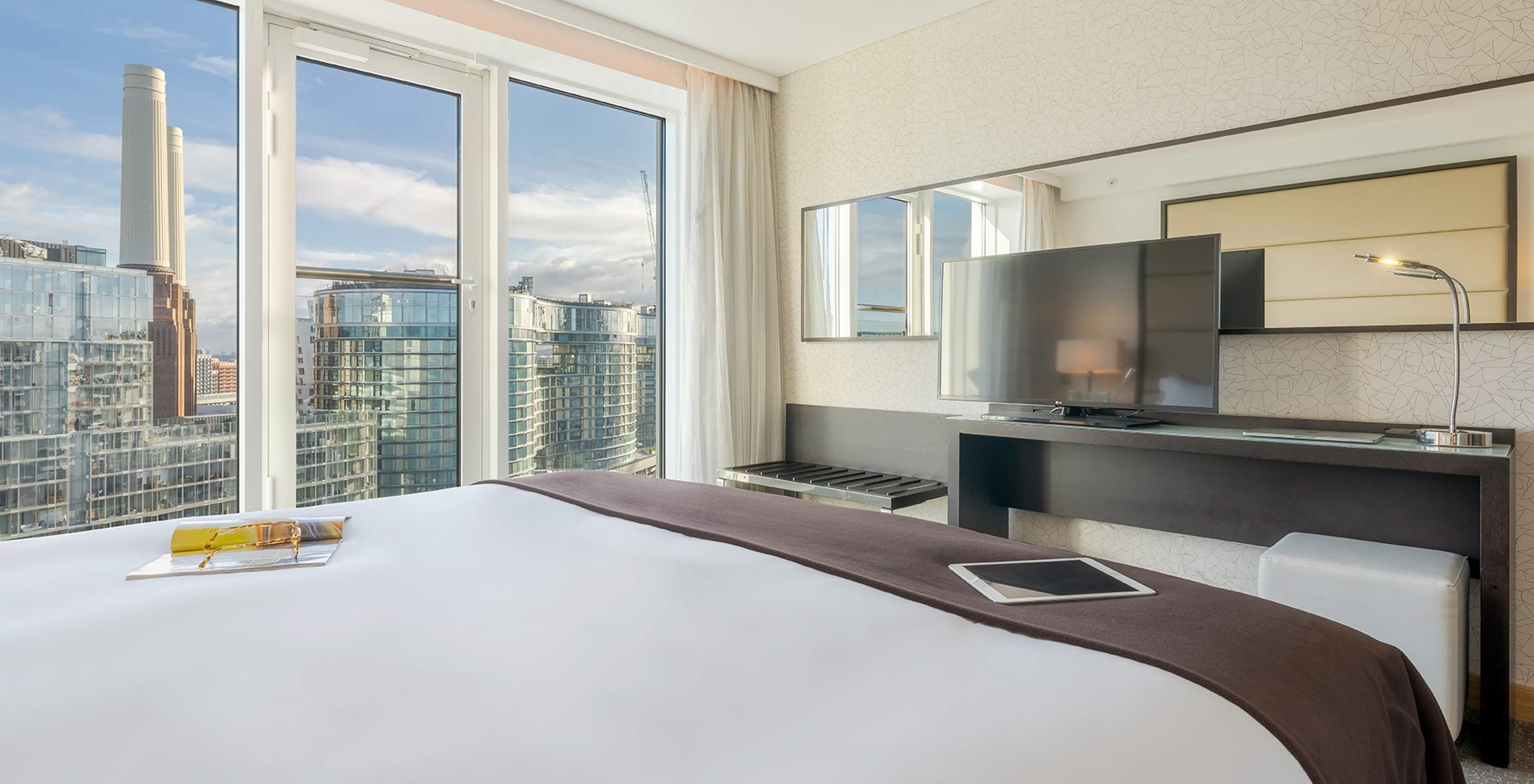 Le Superior King du Pestana Chelsea Bridge a lit double, bureau avec télé, canapé et fenêtres donnant sur la ville