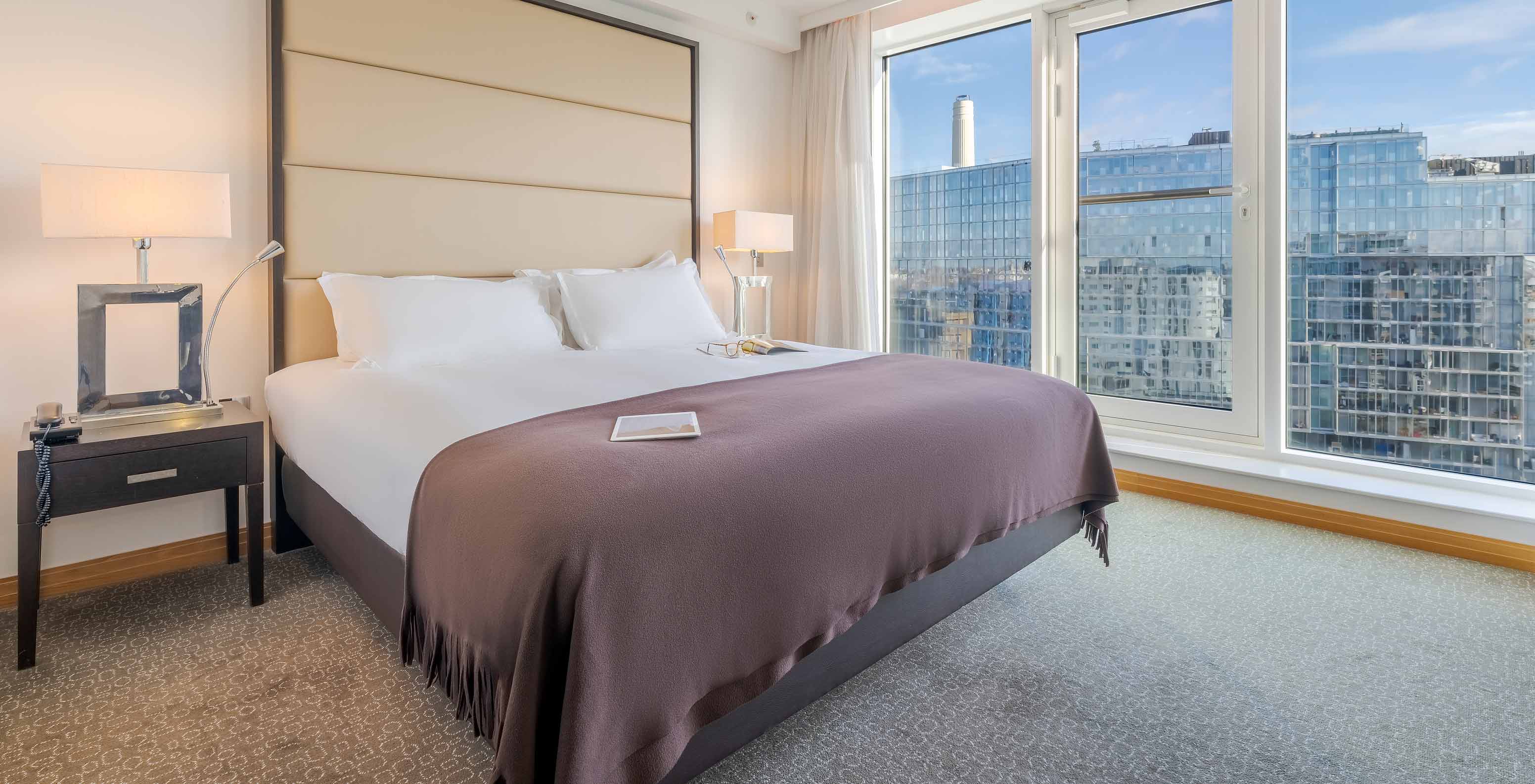 Le Superior King du Pestana Chelsea Bridge a lit double avec draps blancs et grande fenêtre avec vue sur la ville