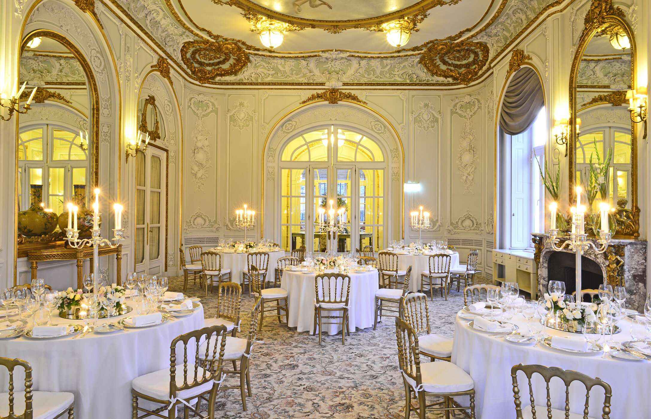 Mariage dans une salle élégante, avec tapis à motifs, murs ornés de détails dorés et tables avec des arrangements floraux