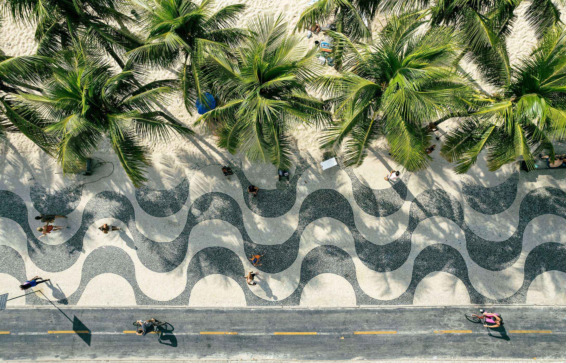 Luchtzicht op het trottoir van Avenida Atlântica met palmbomen en wit zand tegenover het strand van Copacabana in Brazilië