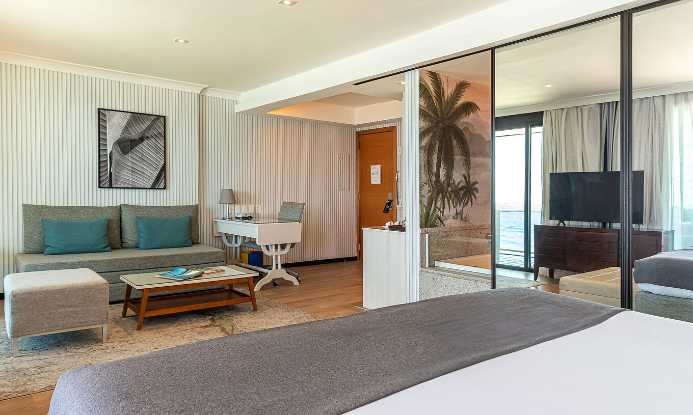 De Suite aan het strand van Pestana Rio Atlântica heeft moderne kamer met bed, bank, tafel en tv.
