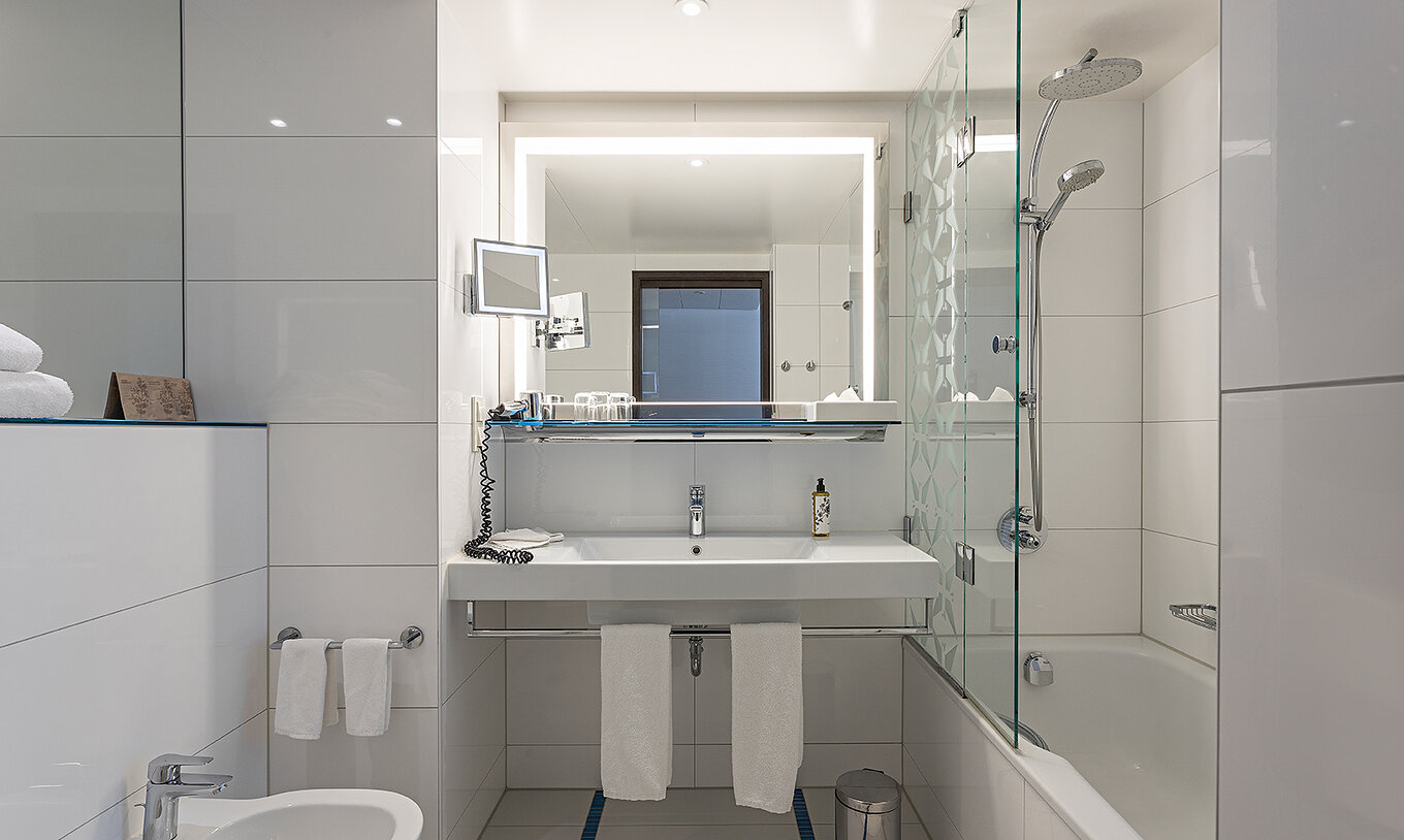 Family Deluxe met badkamer met bad, douche, wastafel en spiegel