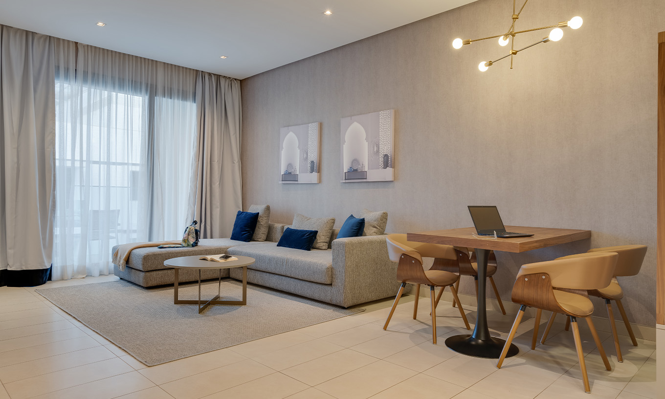 De Premium Familiale Superior Suite van Pestana Casablanca heeft een grote grijze bank met chaise longue bij het raam