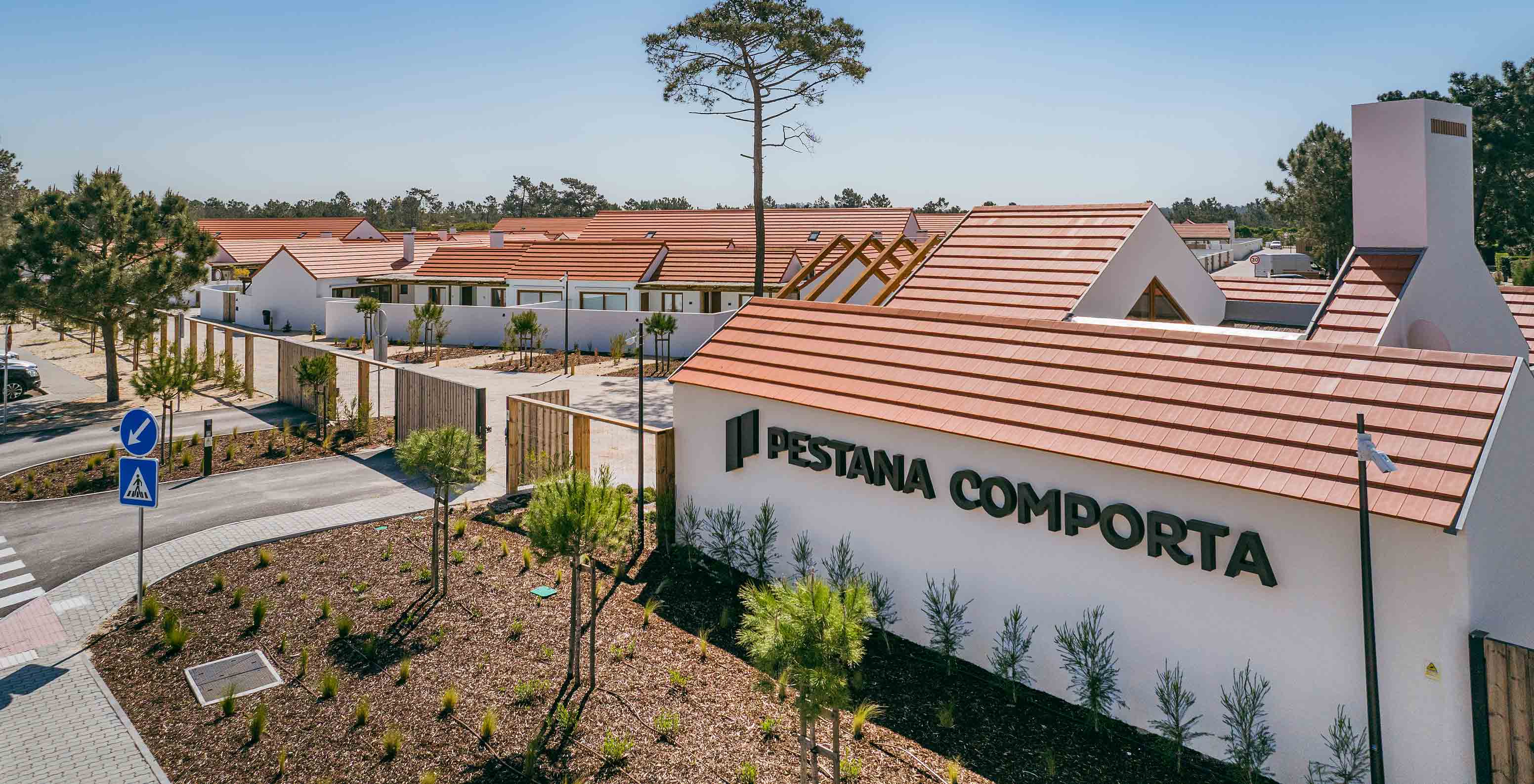 Uitzicht op Pestana Comporta Village Residences, bestaande uit villa's met rode daken, omgeven door vegetatie en bomen