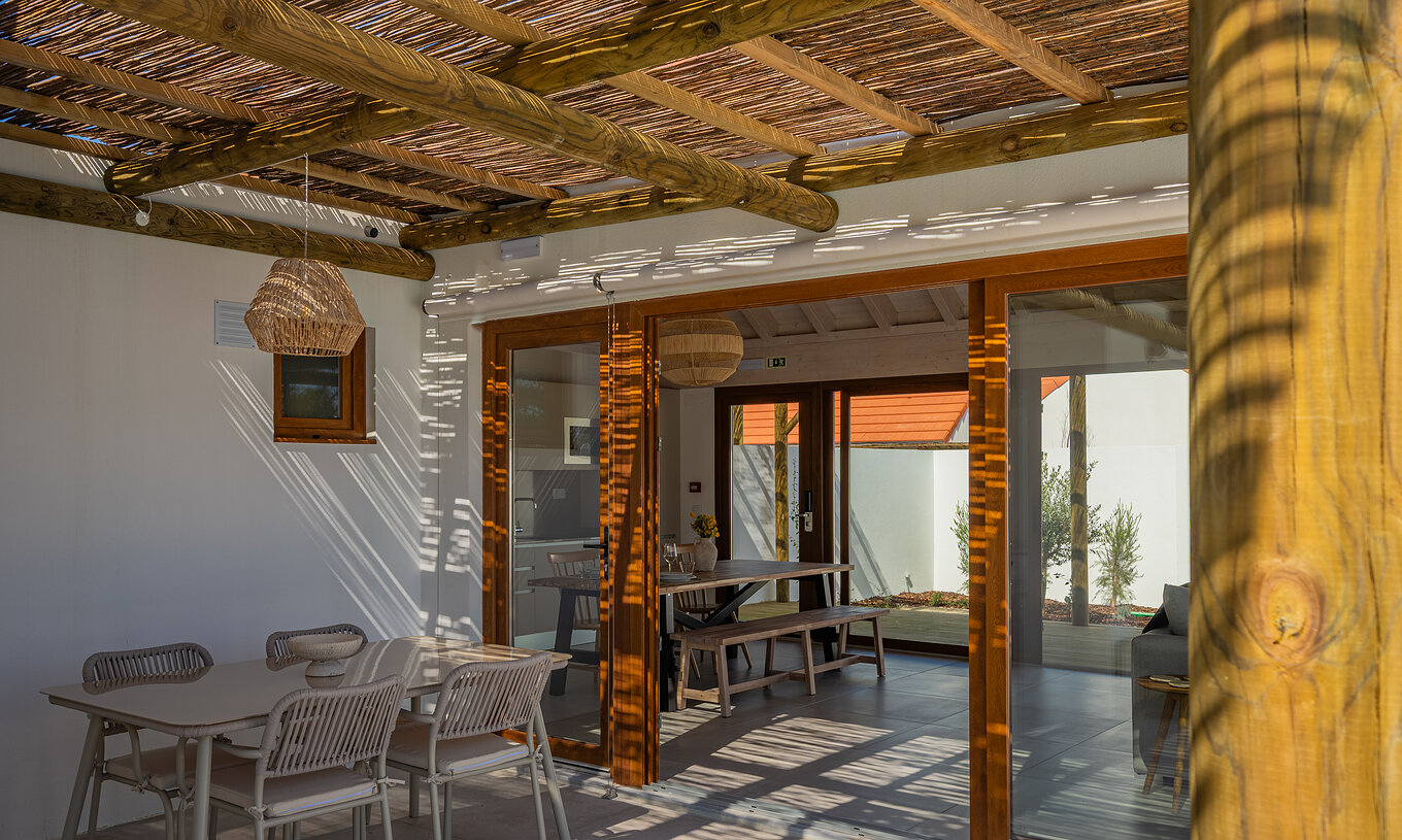 De Premium Groene Villa bij Pestana Comporta Village Residences heeft een overdekte patio met een tafel die naar binnen leidt