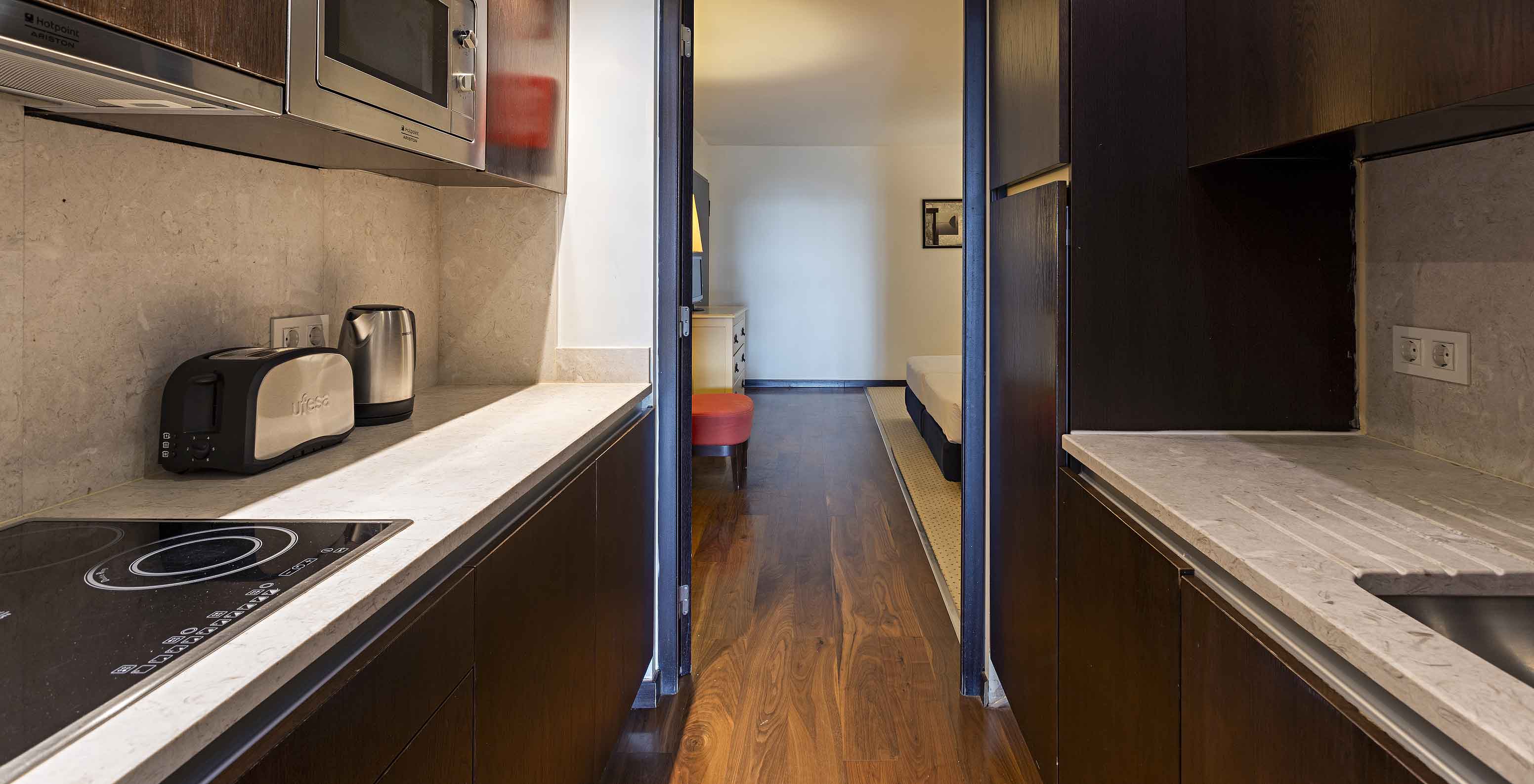 De Cliff Suite T2 in Pestana Alvor Praia heeft een uitgeruste keuken in donker hout en steen, met fornuis en magnetron