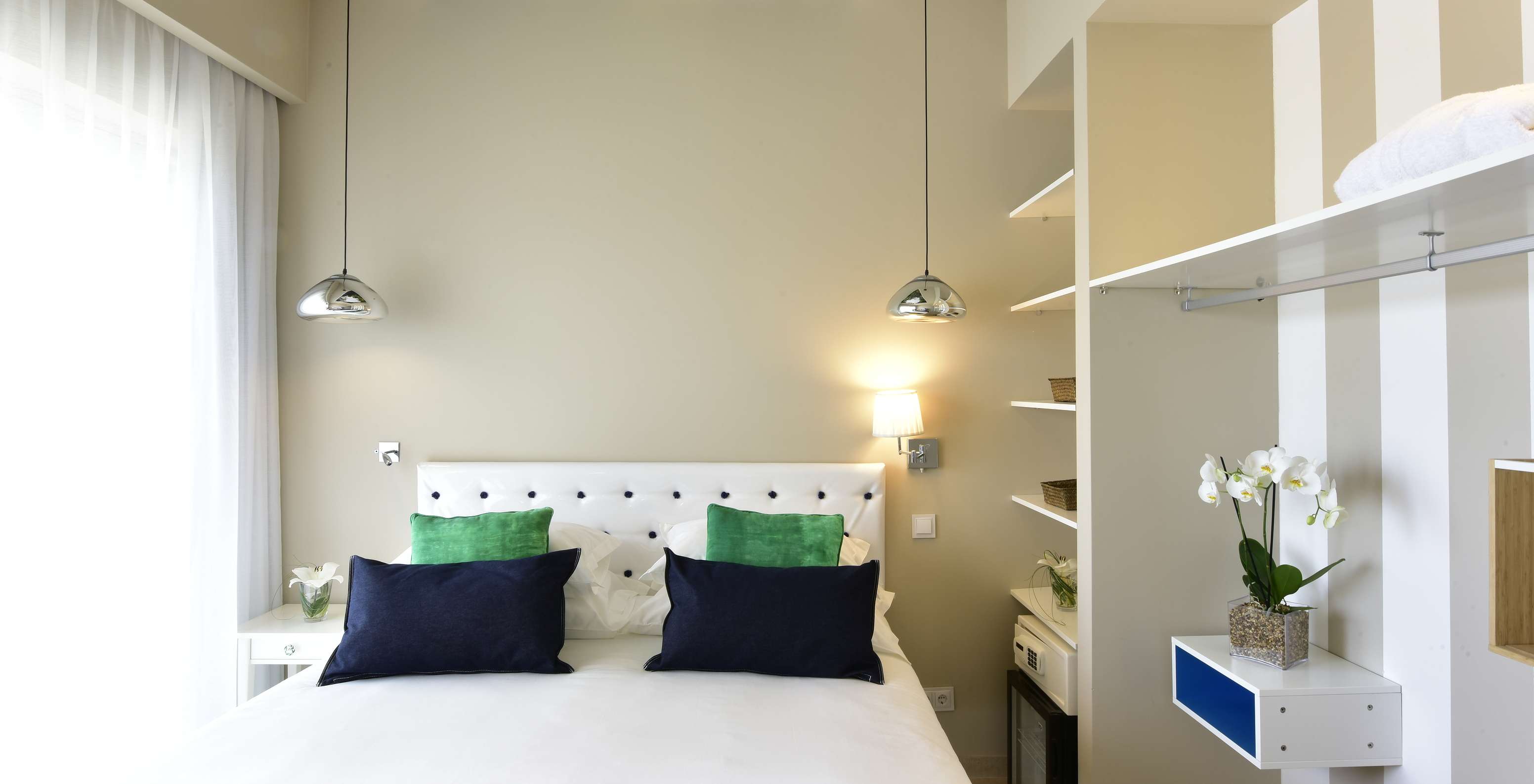 De Suite van Pestana Alvor South Beach heeft tweepersoonsbed met raam aan de ene kant en open kast met minibar aan de andere