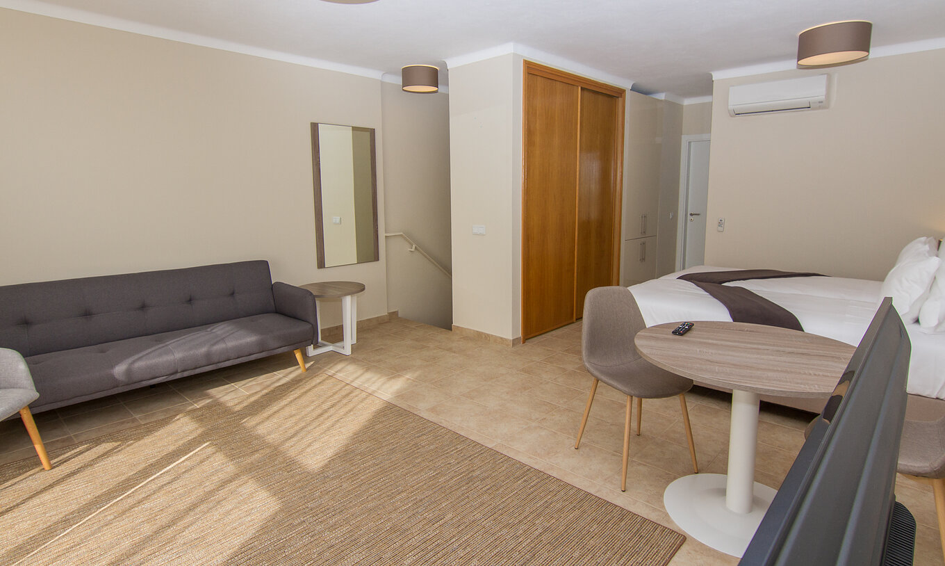 De Studio van Pestana Gramacho Residences heeft een grote bank, een tafel en een stoel, airconditioning en een wandkast