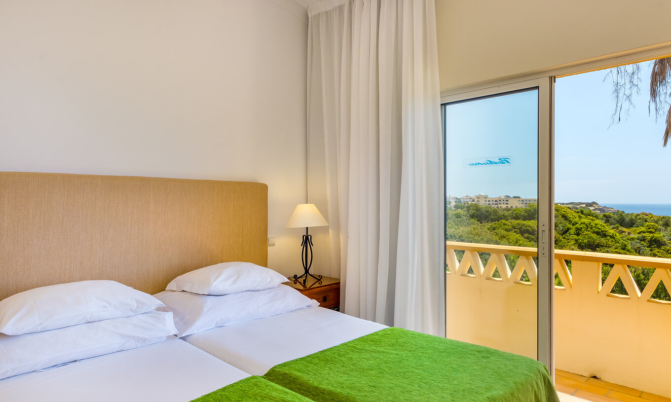 Het Appartement T2 Superior van Pestana Palm Gardens heeft twee bedden bij elkaar met groene dekbed en balkon met uitzicht