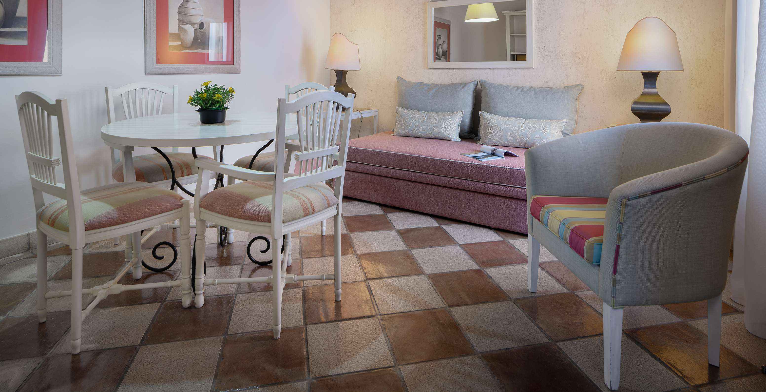 De Suite Tuinzicht van Pestana Vila Sol - Vilamoura heeft een kamer met een bank, tafel, stoelen en een spiegel aan de muur