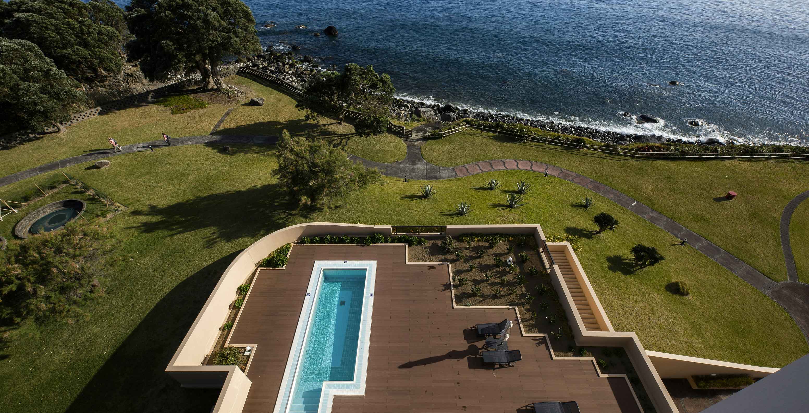 Zwembad van Pestana Bahia Praia op houten terras met uitzicht op zee en groene omgeving