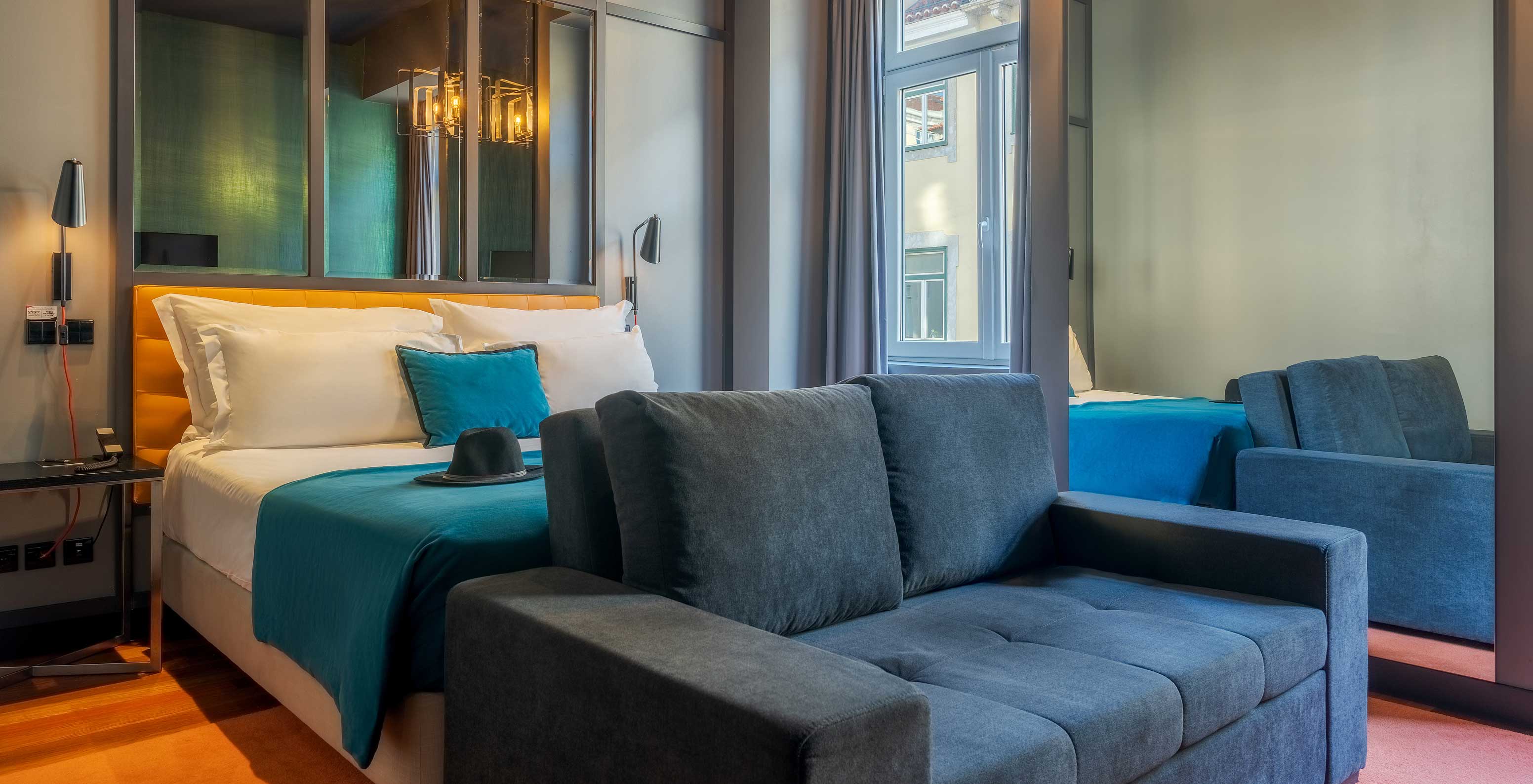 De CR7 Familiar Hat-Trick heeft een sofa een bed en een spiegel boven het bed in Pestana CR7 Lisboa