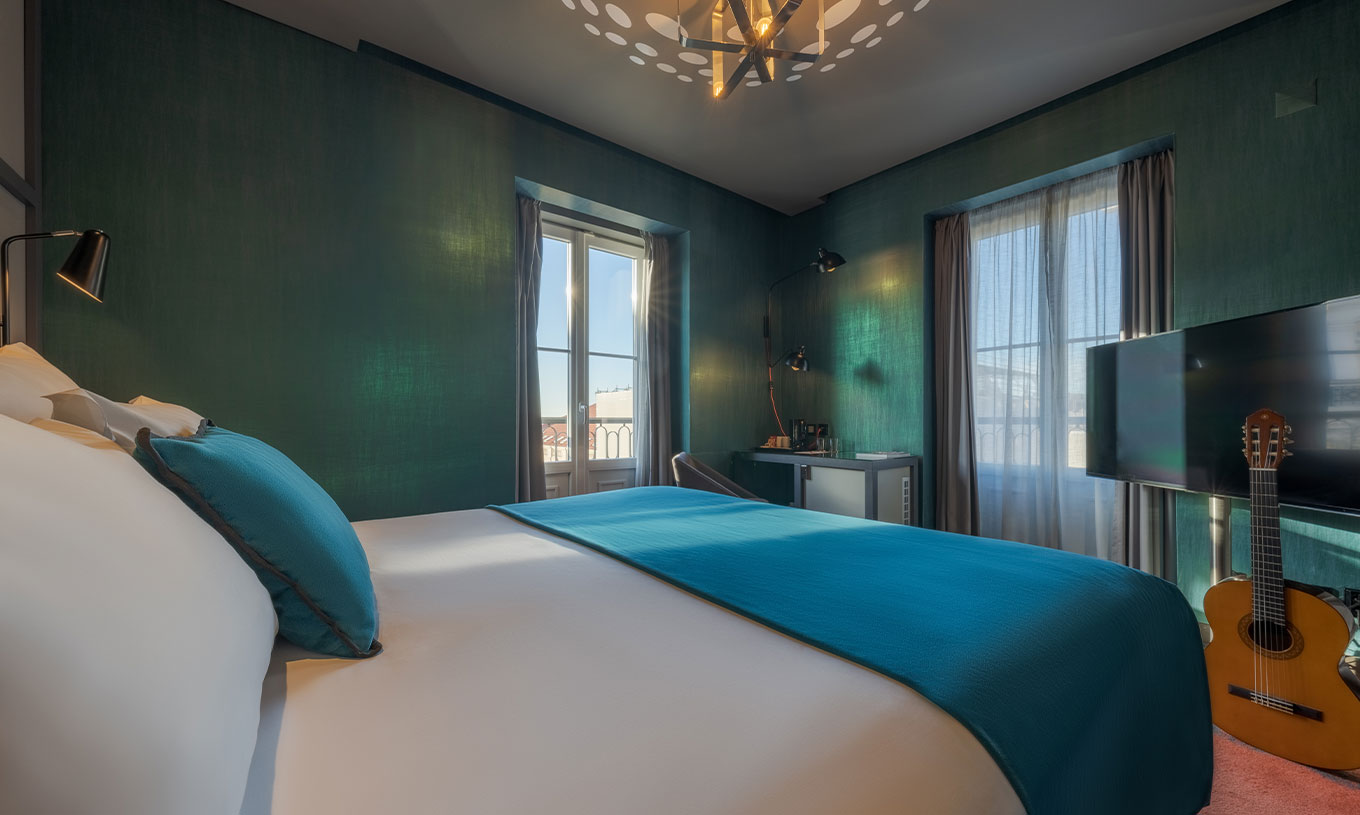 De CR7 Superior Corner van Pestana CR7 Lisboa heeft een bed en twee ramen met uitzicht op het Historisch Centrum van Lisboa