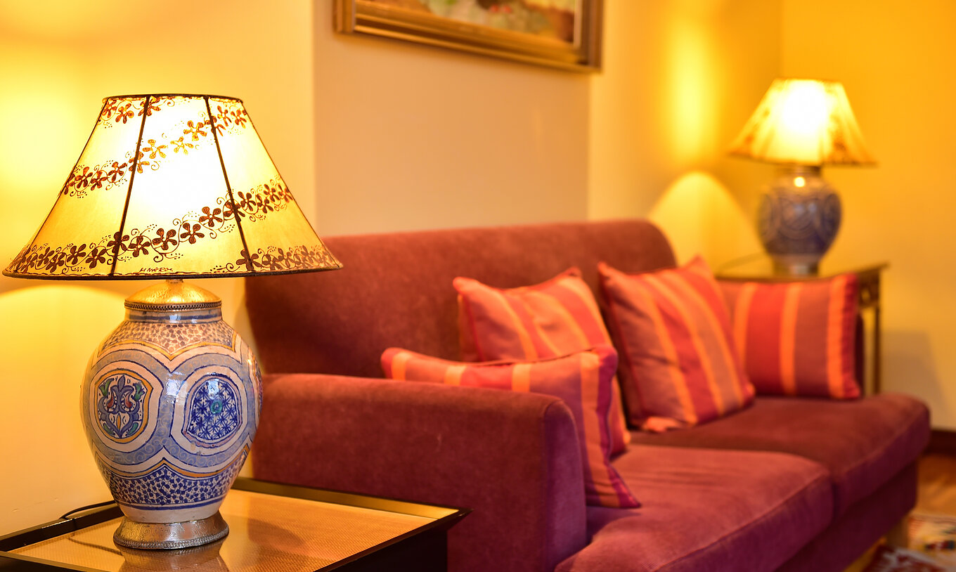 De Superior Suite van Pestana Sintra Golf heeft een bank voor twee personen in rode tint en twee tafels met lampen