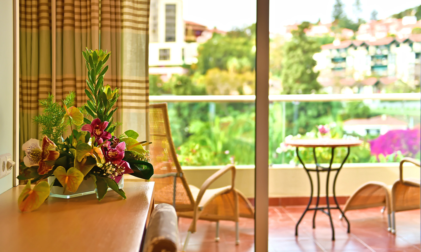 De Classic Twin Pool View van Pestana Carlton Madeira heeft een dressoir met bloemen en een balkon met tafel en stoelen