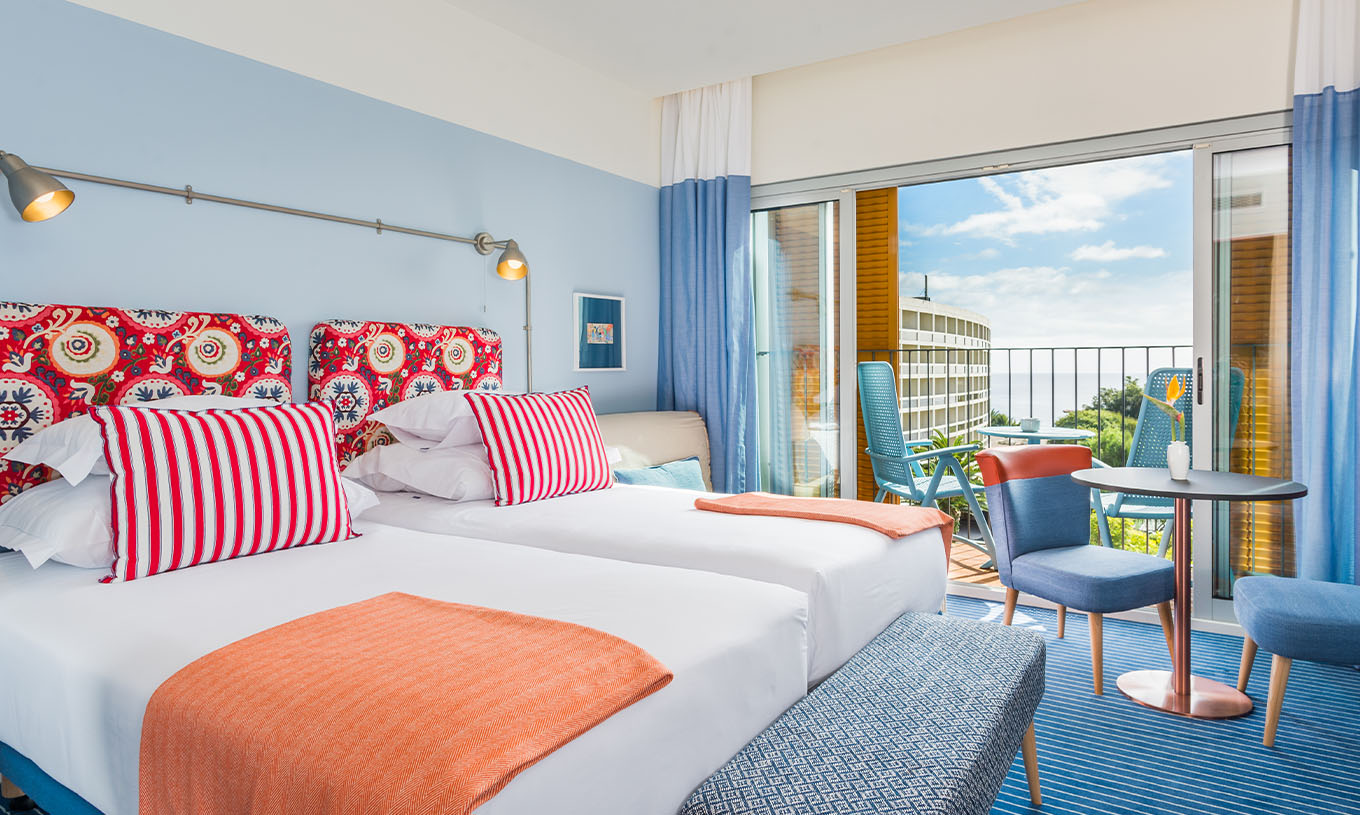 Het Deluxe Studio van Pestana Casino Studios heeft twee tweepersoonsbedden met patroon hoofdeinde, balkon en tafel