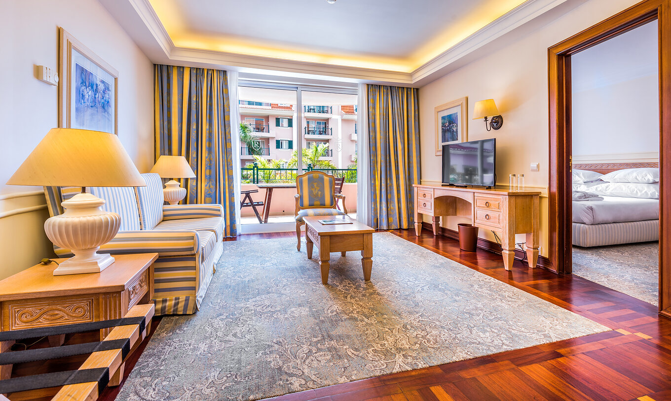 De suite van het Pestana Royal All Inclusive heeft een woonkamer met een tv, stoelen en een balkon.