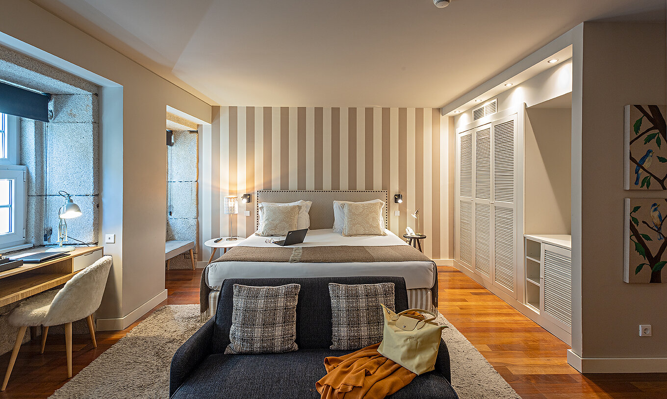 De Heritage Suite van het Pestana Vintage Porto heeft een tweepersoonsbed, een bank, een bureau en een witte kledingkast