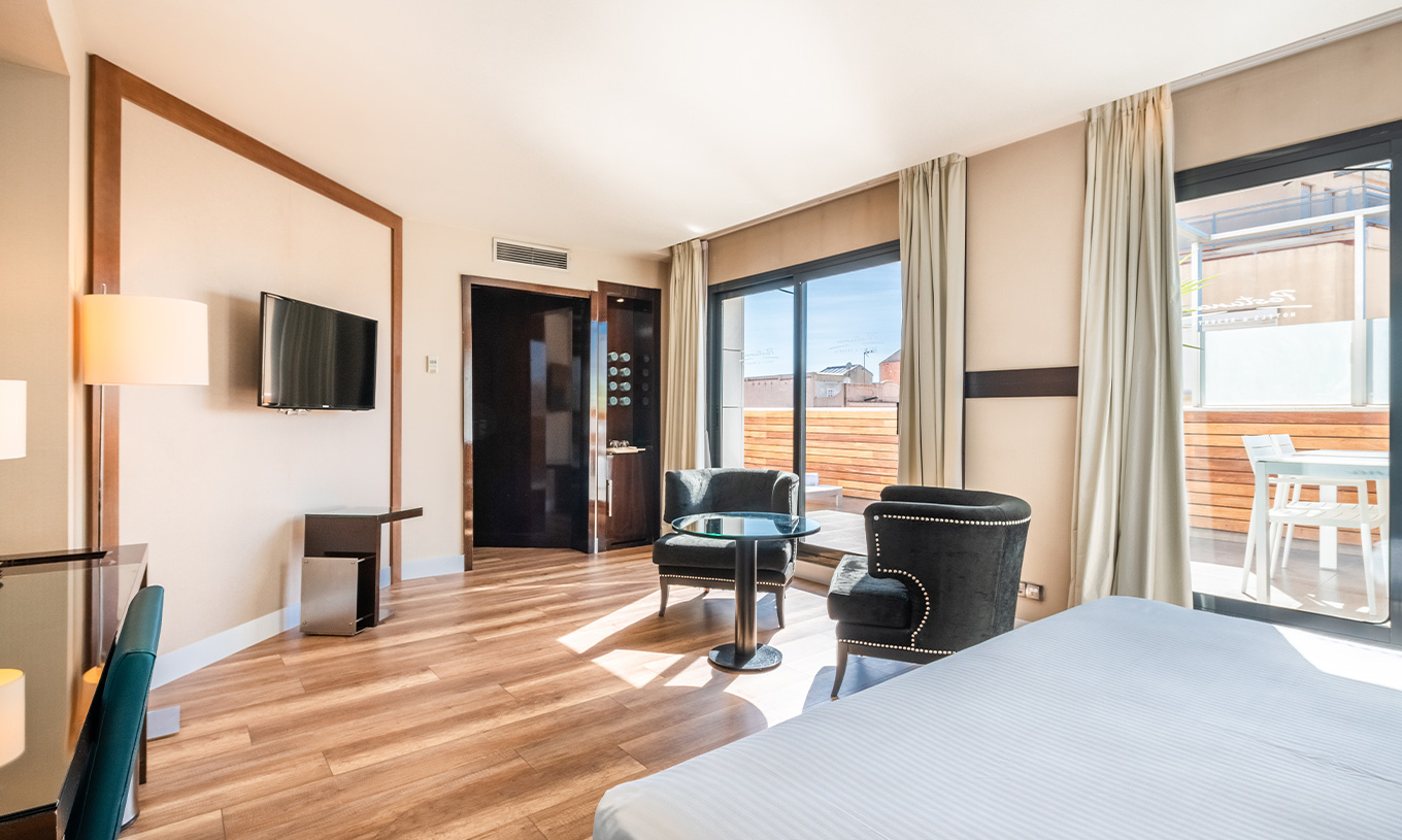 Junior Suite van Pestana Arena Barcelona heeft balkon met tafel en stoelen en uitzicht op stad Barcelona