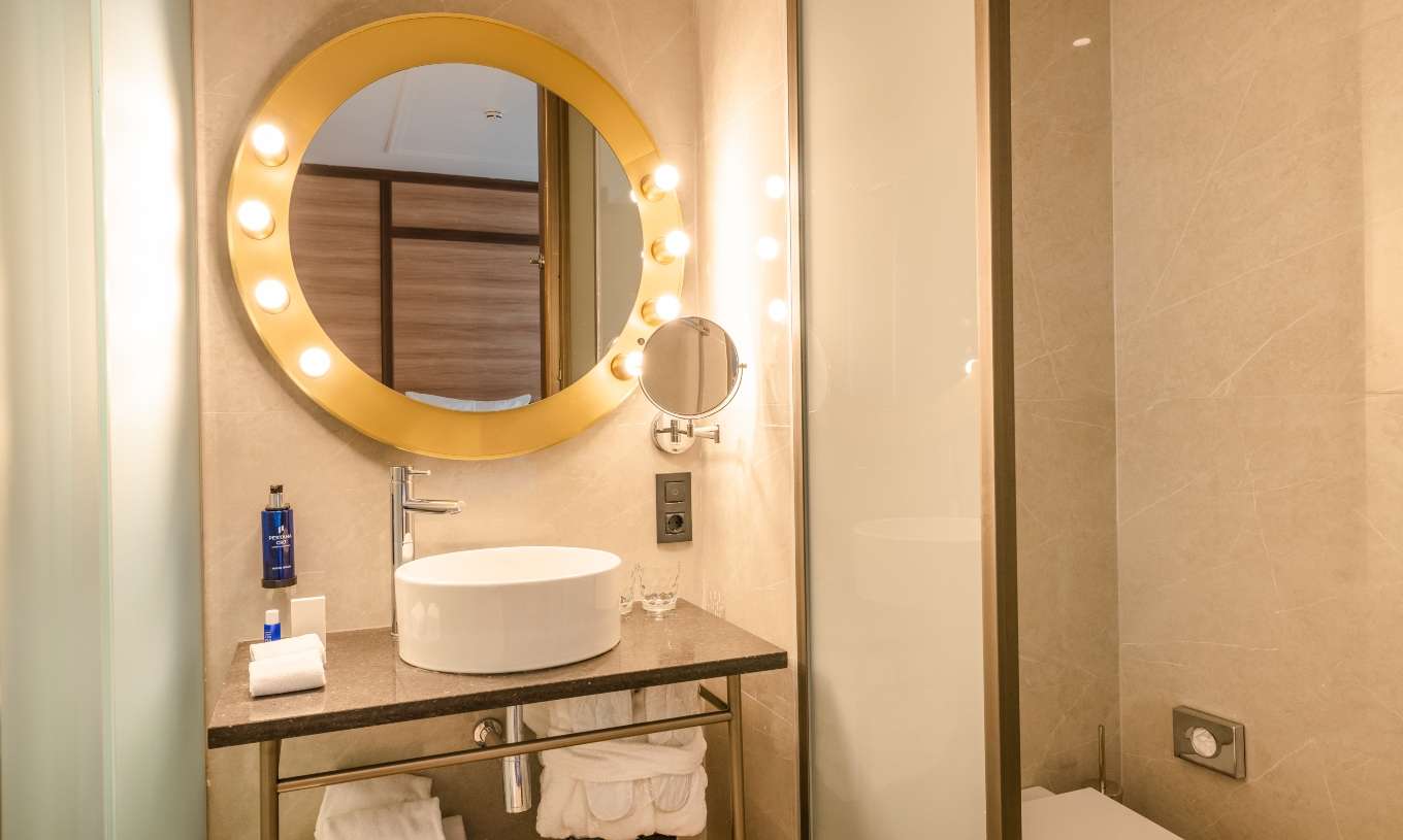 De Gezellige Kamer van Pestana CR7 Gran Vía Madrid heeft een badkamer met een ronde spiegel met lampen