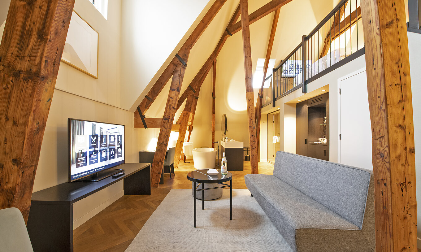 Clock Tower Suite van Pestana Amsterdam Riverside heeft woonkamer met bank, salontafel en televisie