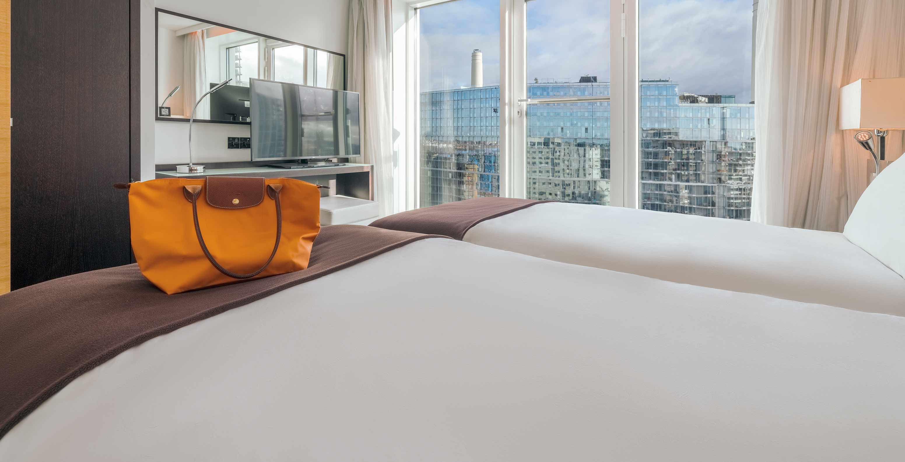 De Superior Twin in het Pestana Chelsea Bridge heeft twee bedden, tv, spiegel, raam met stadszicht en gordijnen