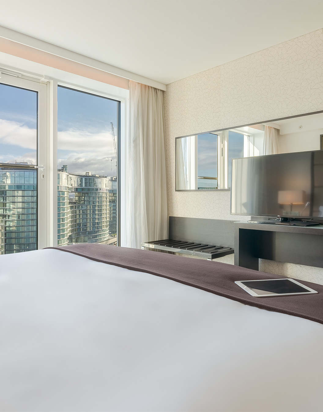 Kamer met tweepersoonsbed, tv, spiegel, grote ramen met uitzicht over Londen