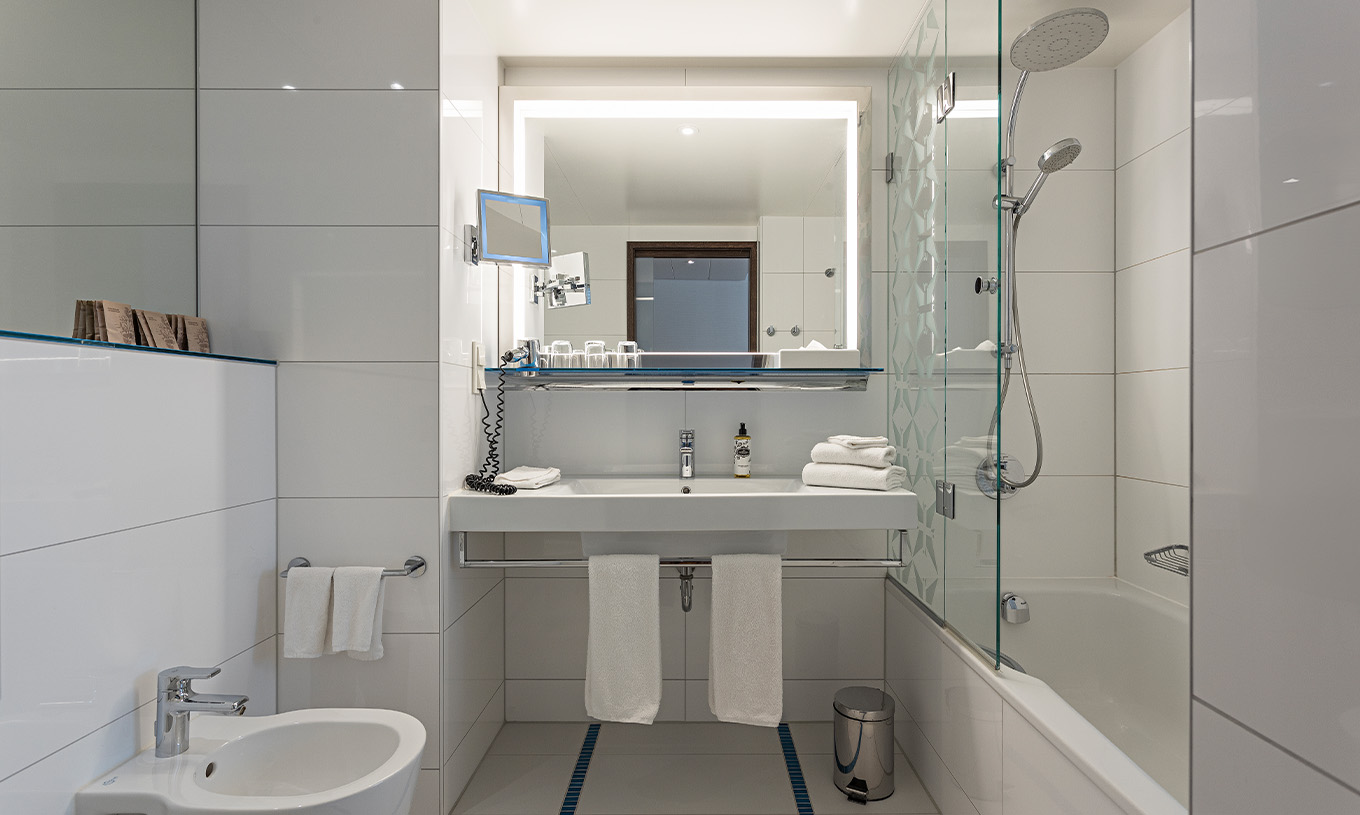 O quarto Deluxe Piso Superior do Pestana Berlin Tiergarten conta com casa de banho com banheira e chuveiro, e um lavatório