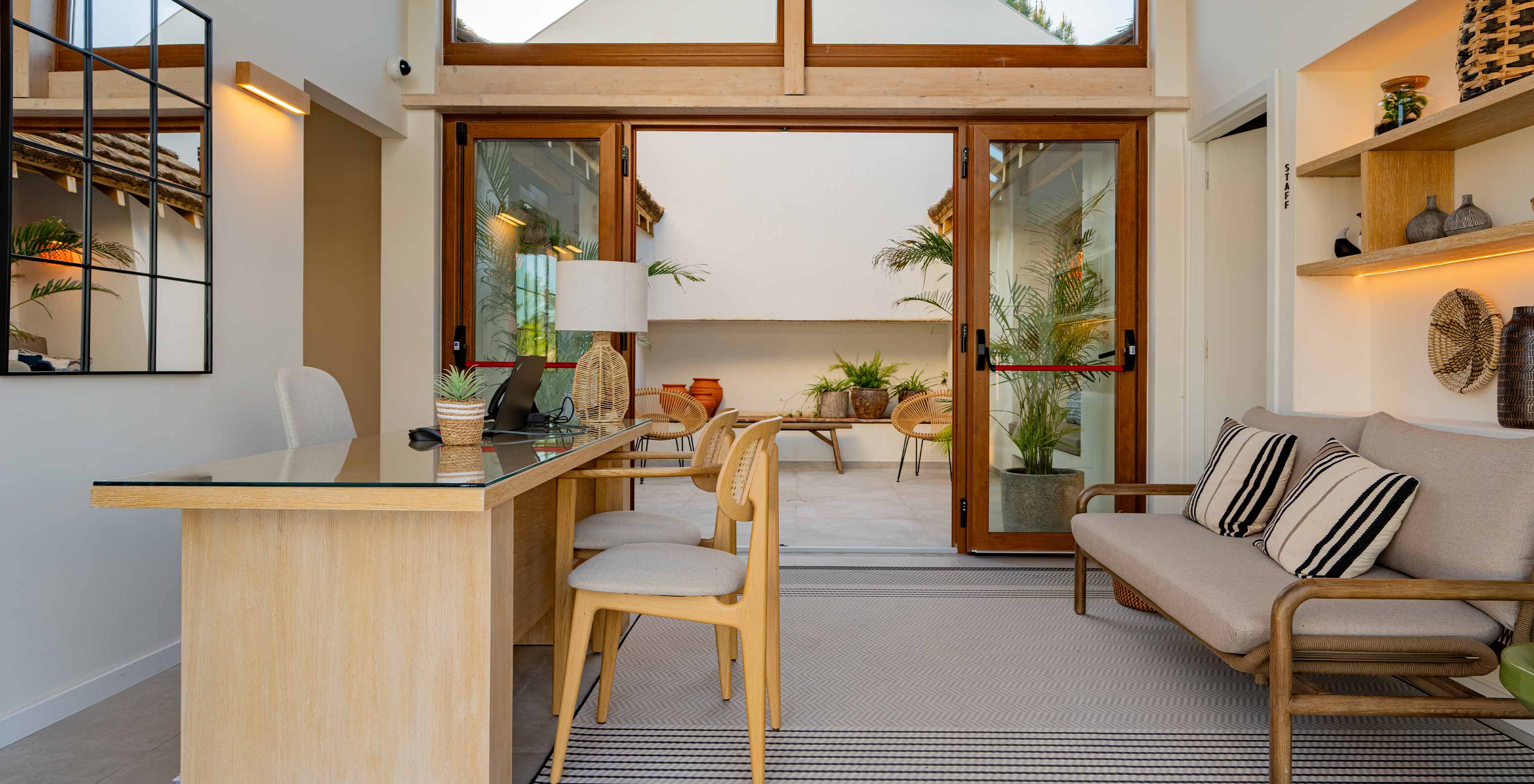 Receção moderna e acolhedora com um sofá e portas duplas de vidro, no Pestana Comporta Village Residences