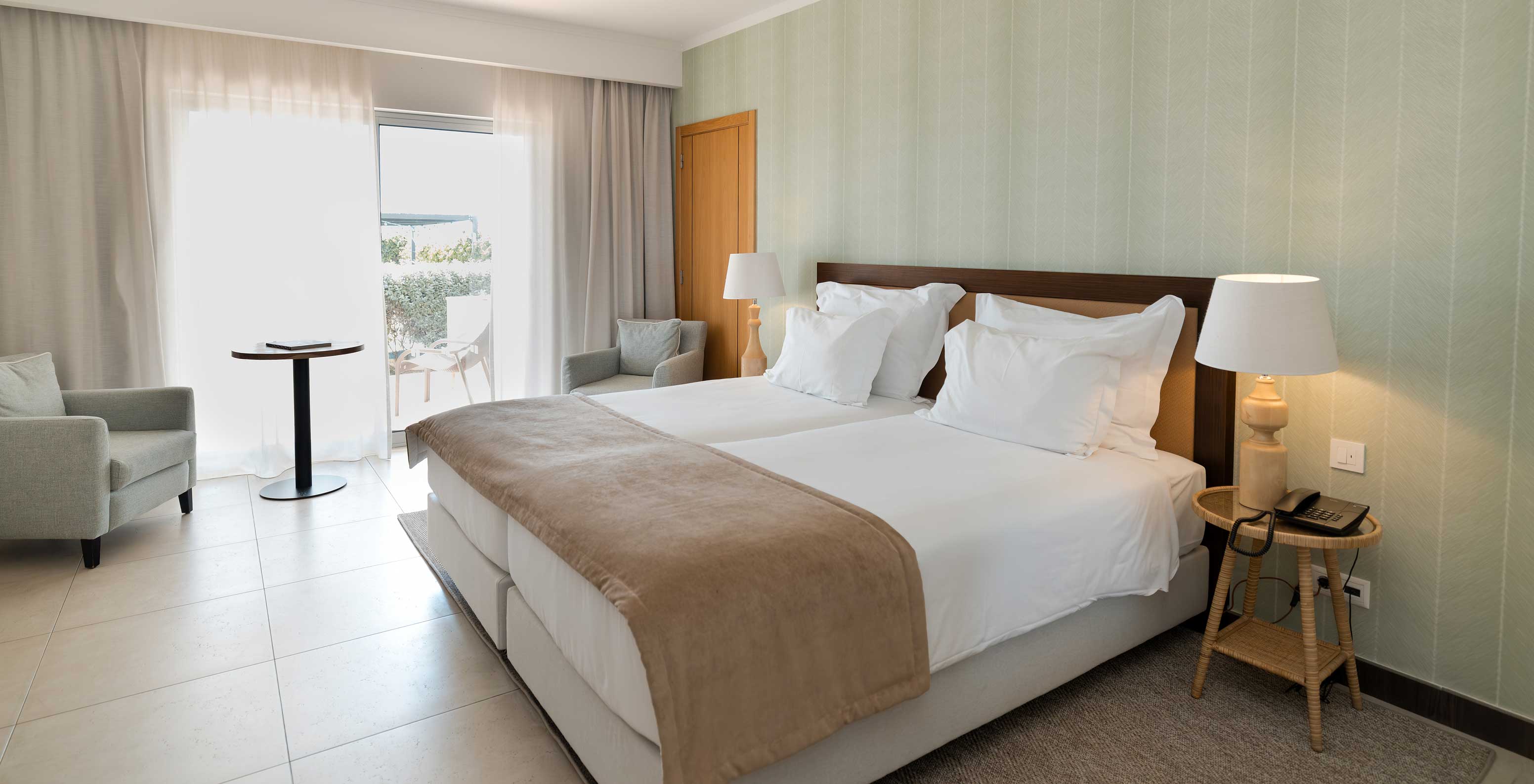 O Estúdio Vista Jardim do Pestana Alvor Beach Villas tem duas camas, papel de parede verde e janela com varanda